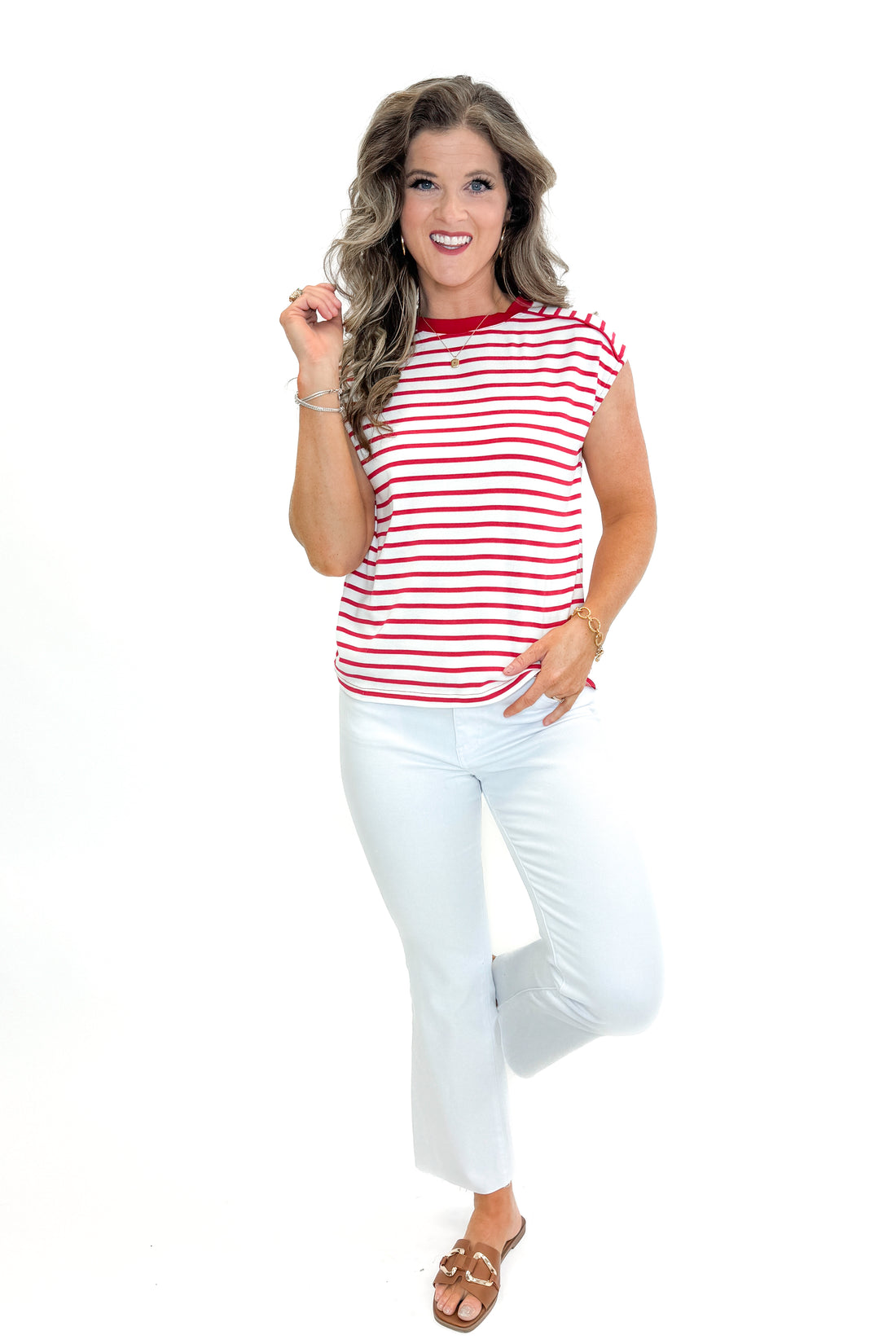 Front view of woman wearing Red Striped Sleeveless Top with white jeans against white studio background.