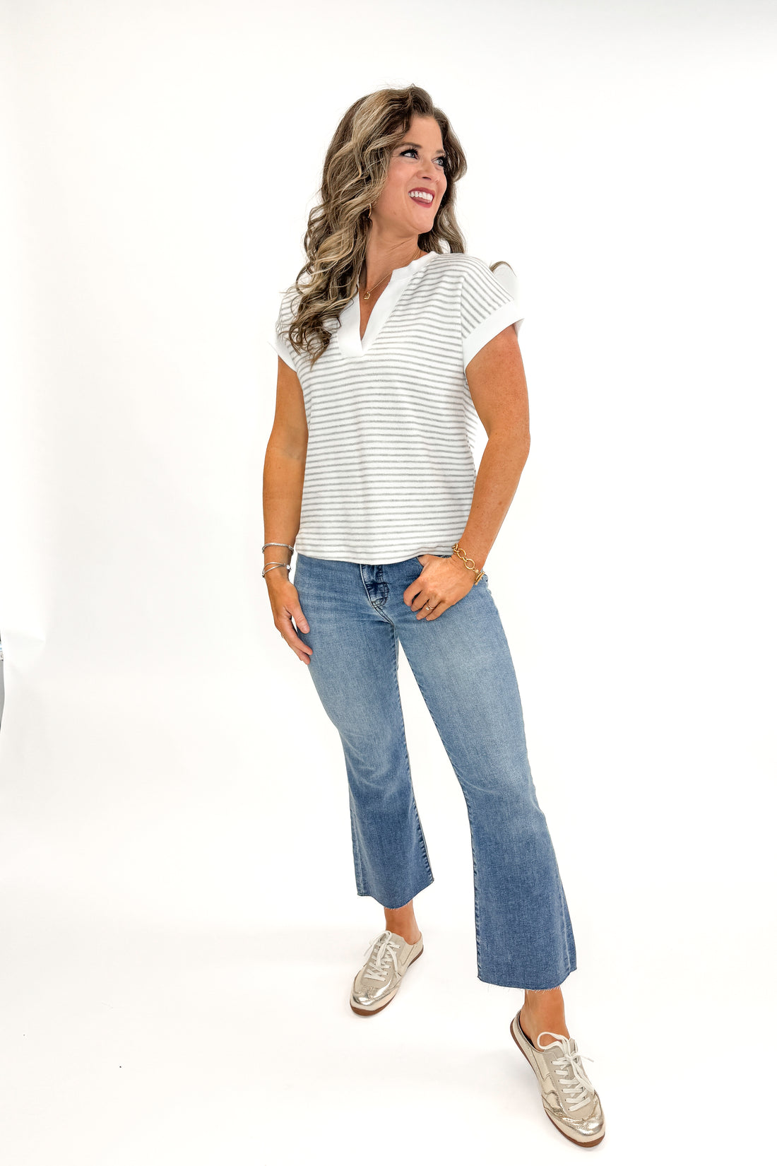 Front view of woman wearing Ivory &amp; Grey Striped Terry Top with jeans against white studio background.