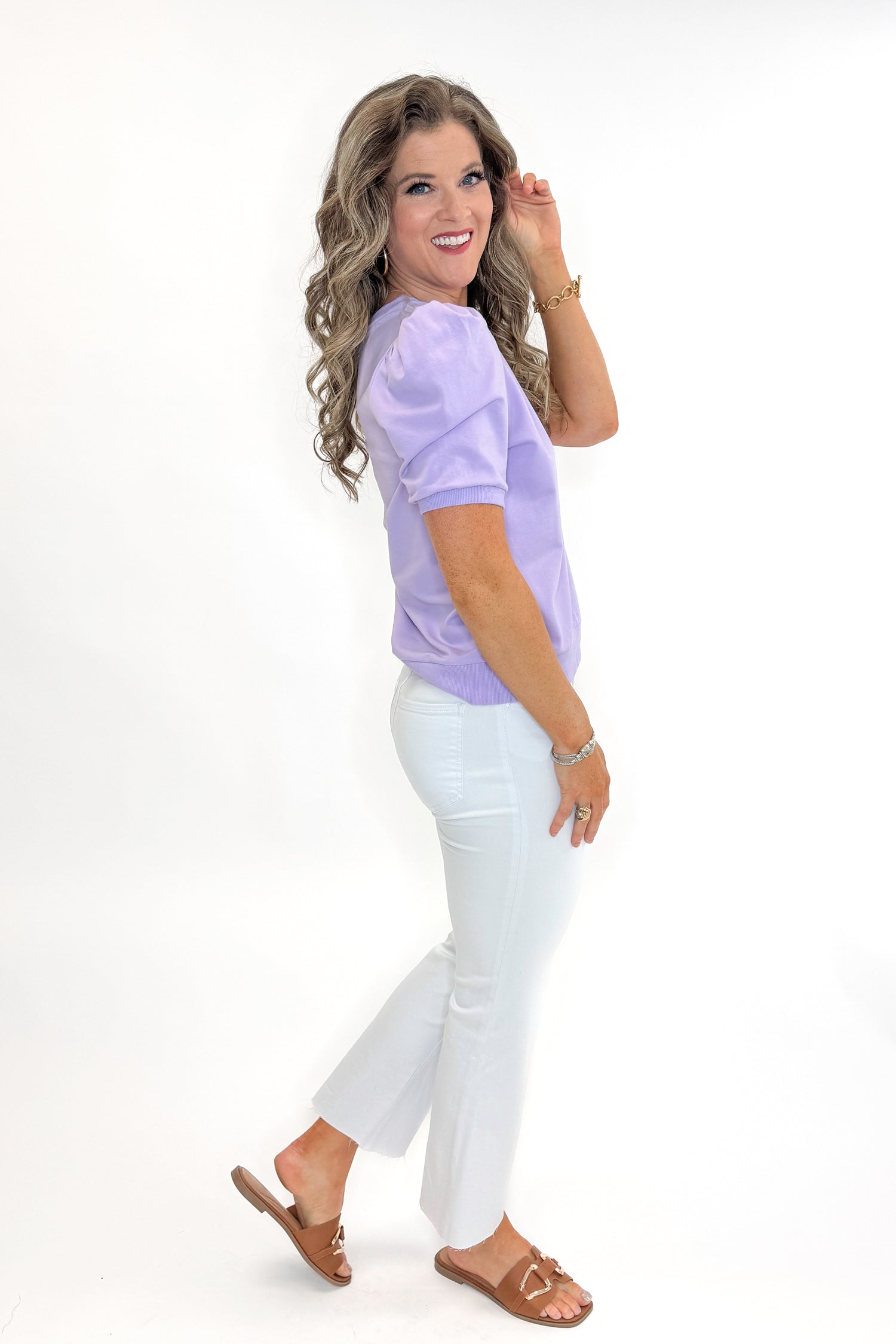 Side view of woman wearing Lavender Short Sleeve Sweatshirt with jeans against white studio background.