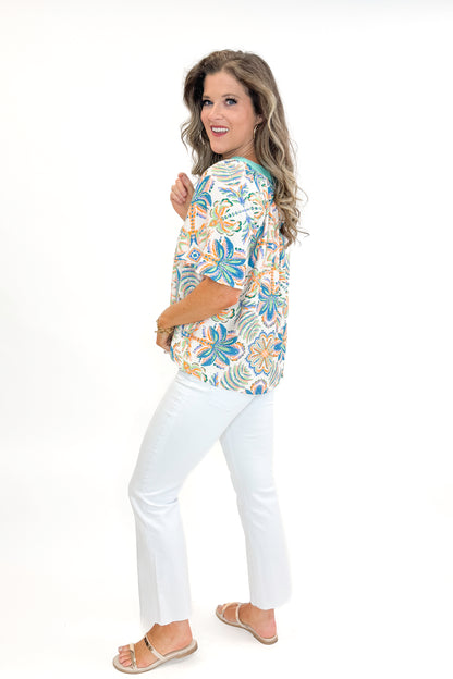 Side view of woman wearing Mint &amp; Multi Tropical Printed Top with jeans against white studio background.