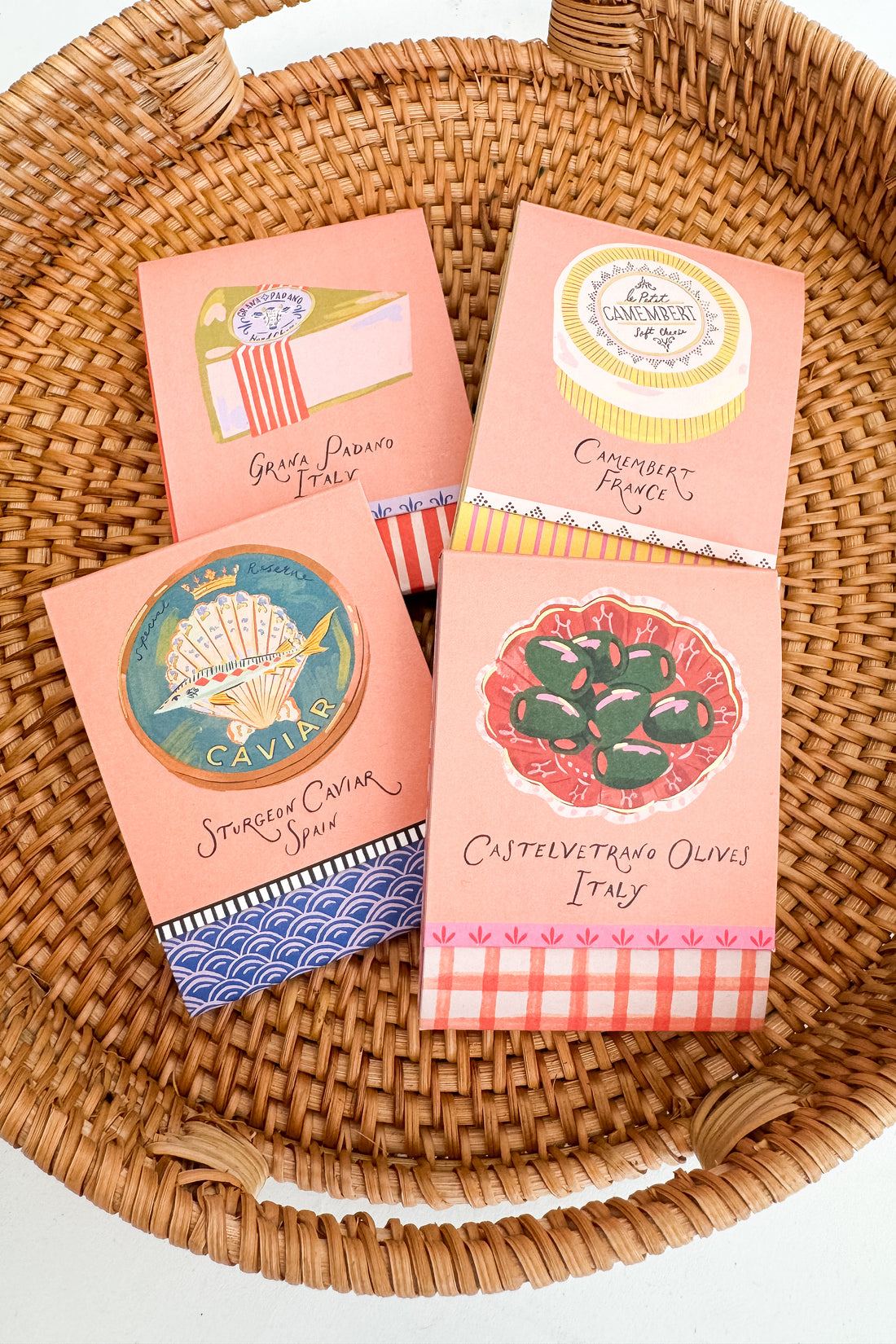 Four pink boxes with colorful labels on a woven basket