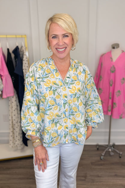Front view of woman wearing Swagger Boutique’s Yellow &amp; Blue Lemon Print 3/4 Sleeve Top with jeans with clothes around.
