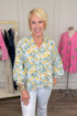 Front view of woman wearing Swagger Boutique’s Yellow & Blue Lemon Print 3/4 Sleeve Top with jeans with clothes around.