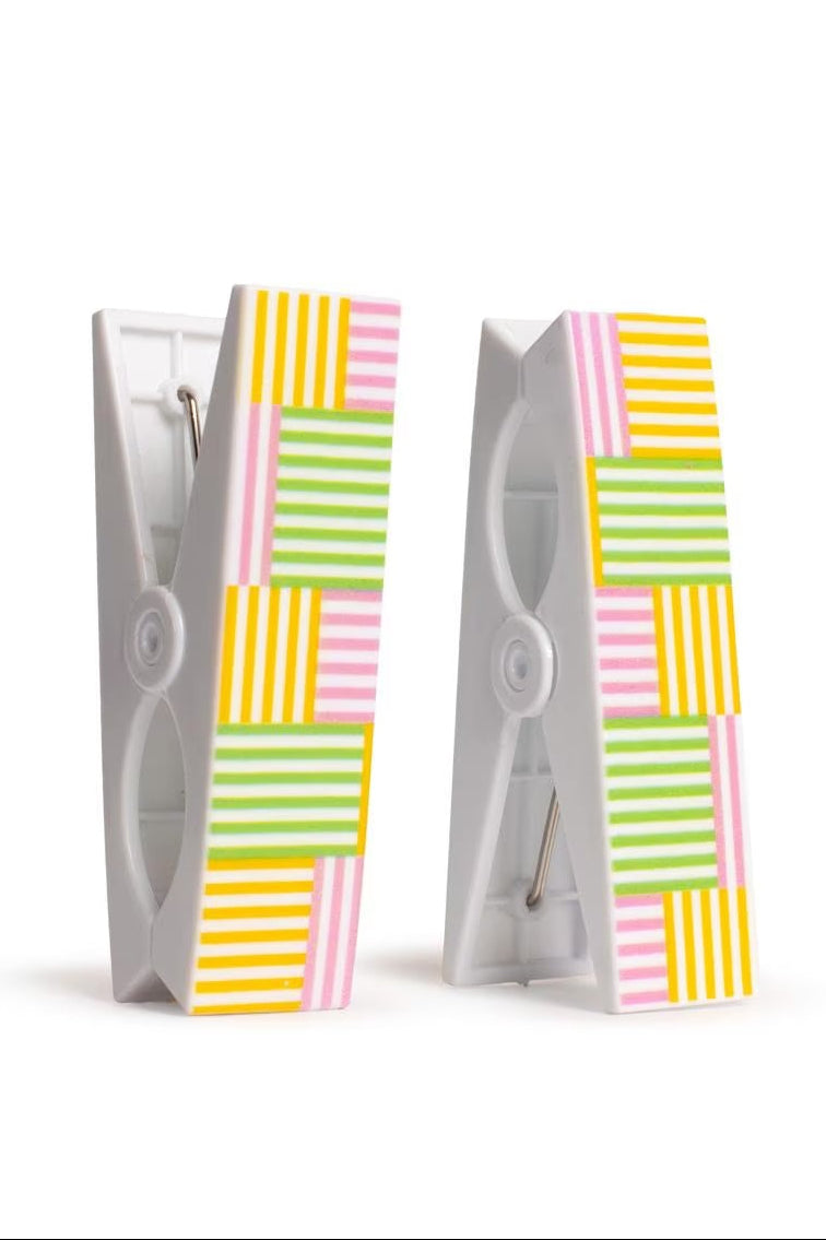 Two beach towel clips with colorful striped designs on a white background