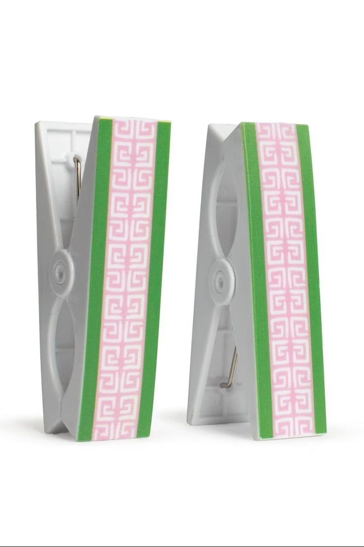 Two beach towel clips with green and pink geometric designs in their packaging on a white background