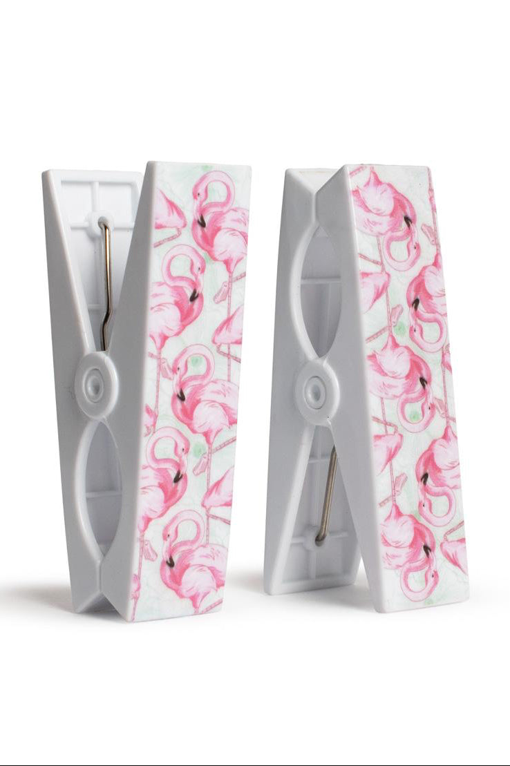 Two white clothespins with pink floral patterns on a white background