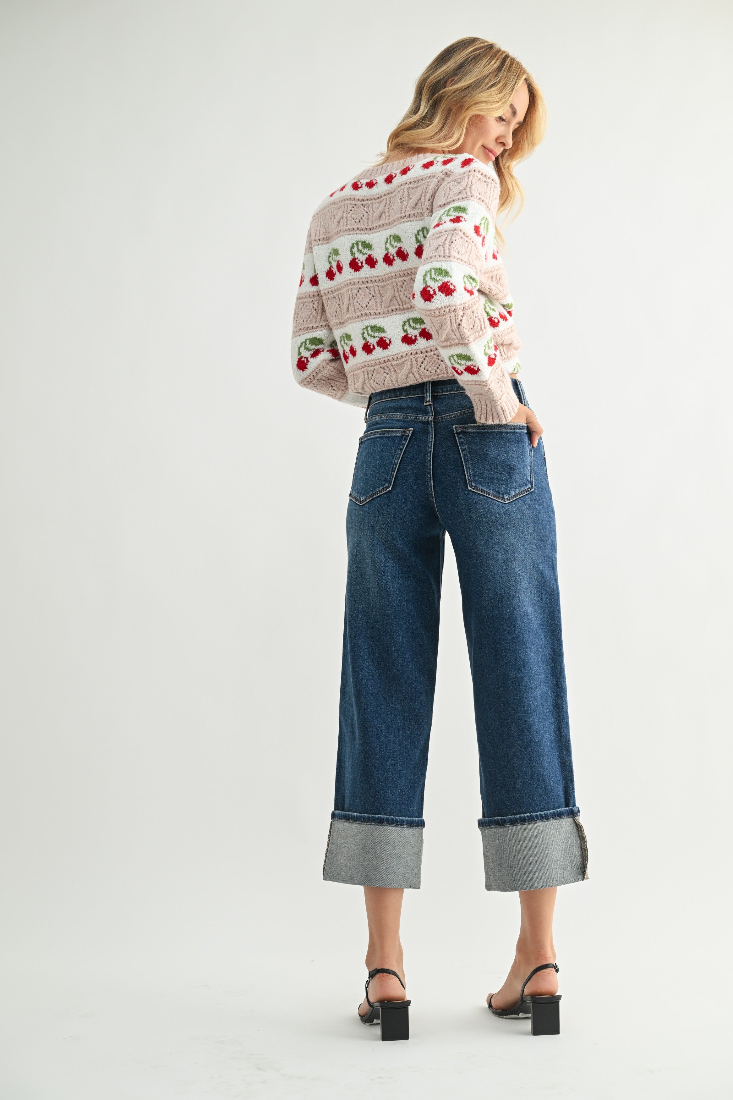 Woman wearing a patterned sweater and blue jeans on a white background