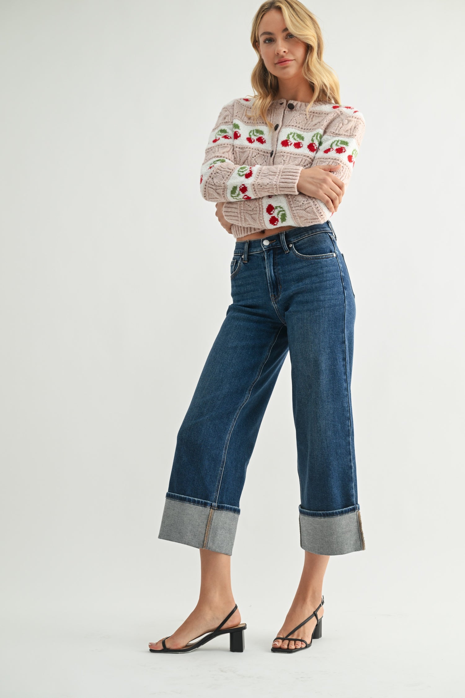 Woman wearing a patterned sweater and blue jeans on a white background