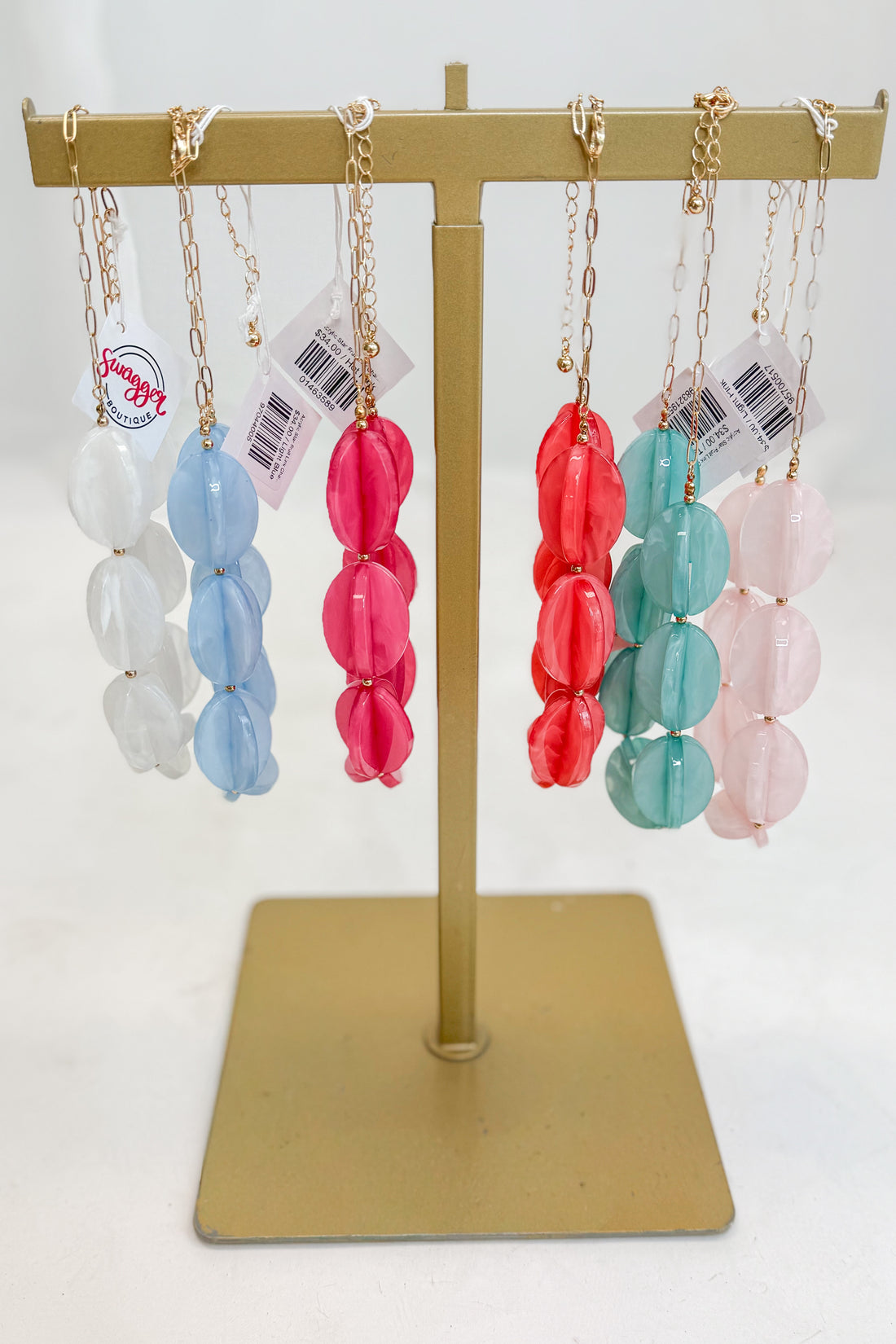 Colorful beaded necklaces on a gold display stand with a white background