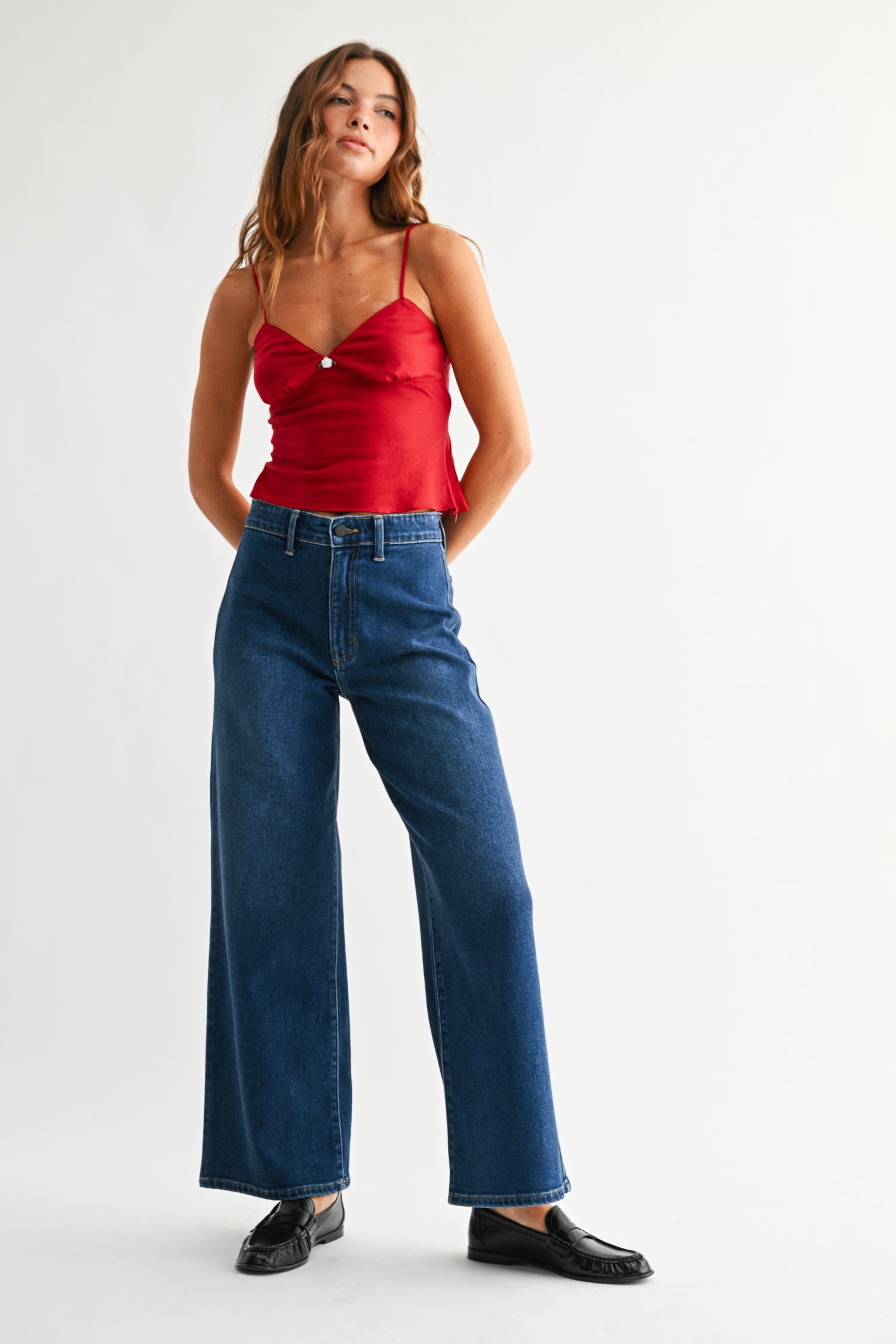 Front view of woman wearing red top with Dark Wash No Pocket Trouser Jeans against white studio background.
