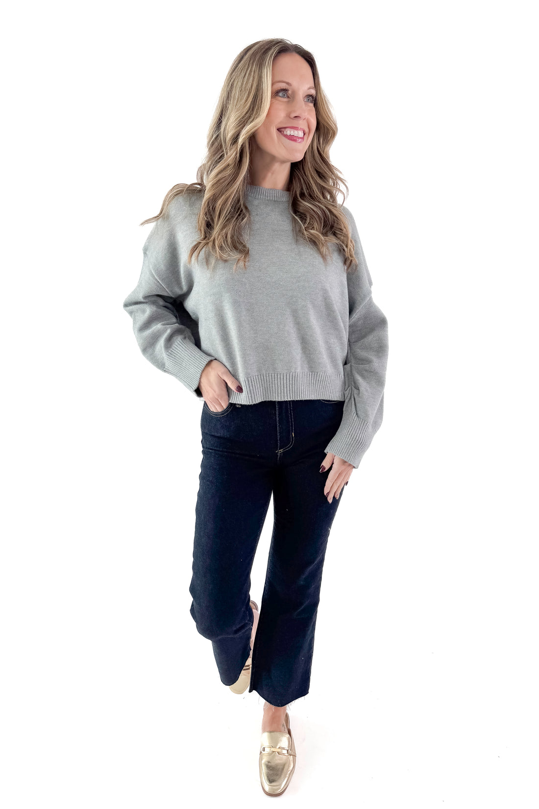Front view of woman wearing Light Grey Crewneck Sweater with Ruched Sleeve with jeans against white studio background.