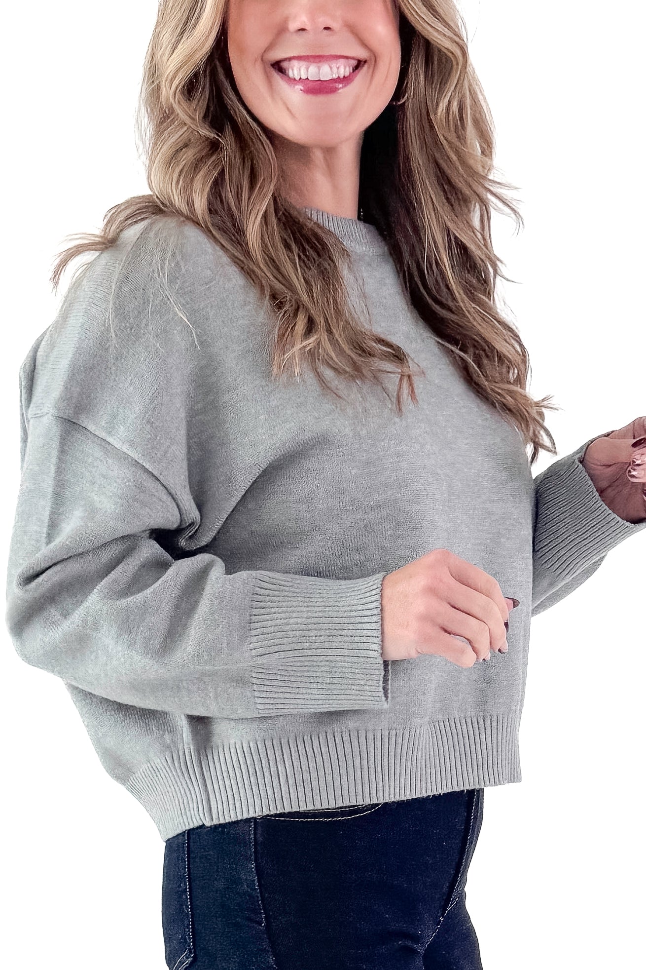 Side view of woman wearing Light Grey Crewneck Sweater with Ruched Sleeve with jeans against white studio background.