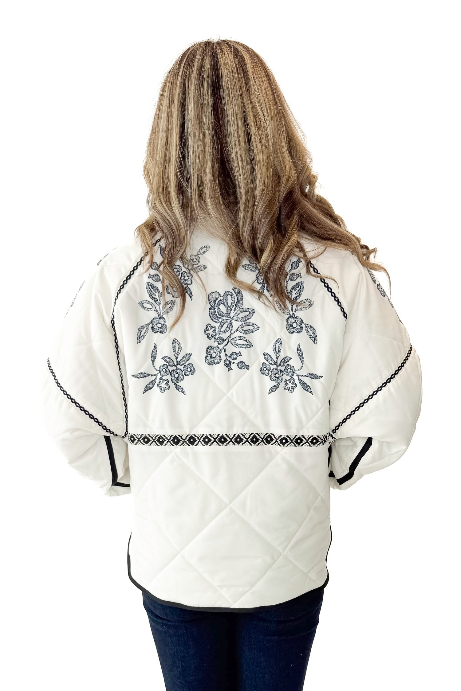 Back view of woman wearing Cream &amp; Navy Embroidery Print Puffer Jacket with jeans against white studio background.