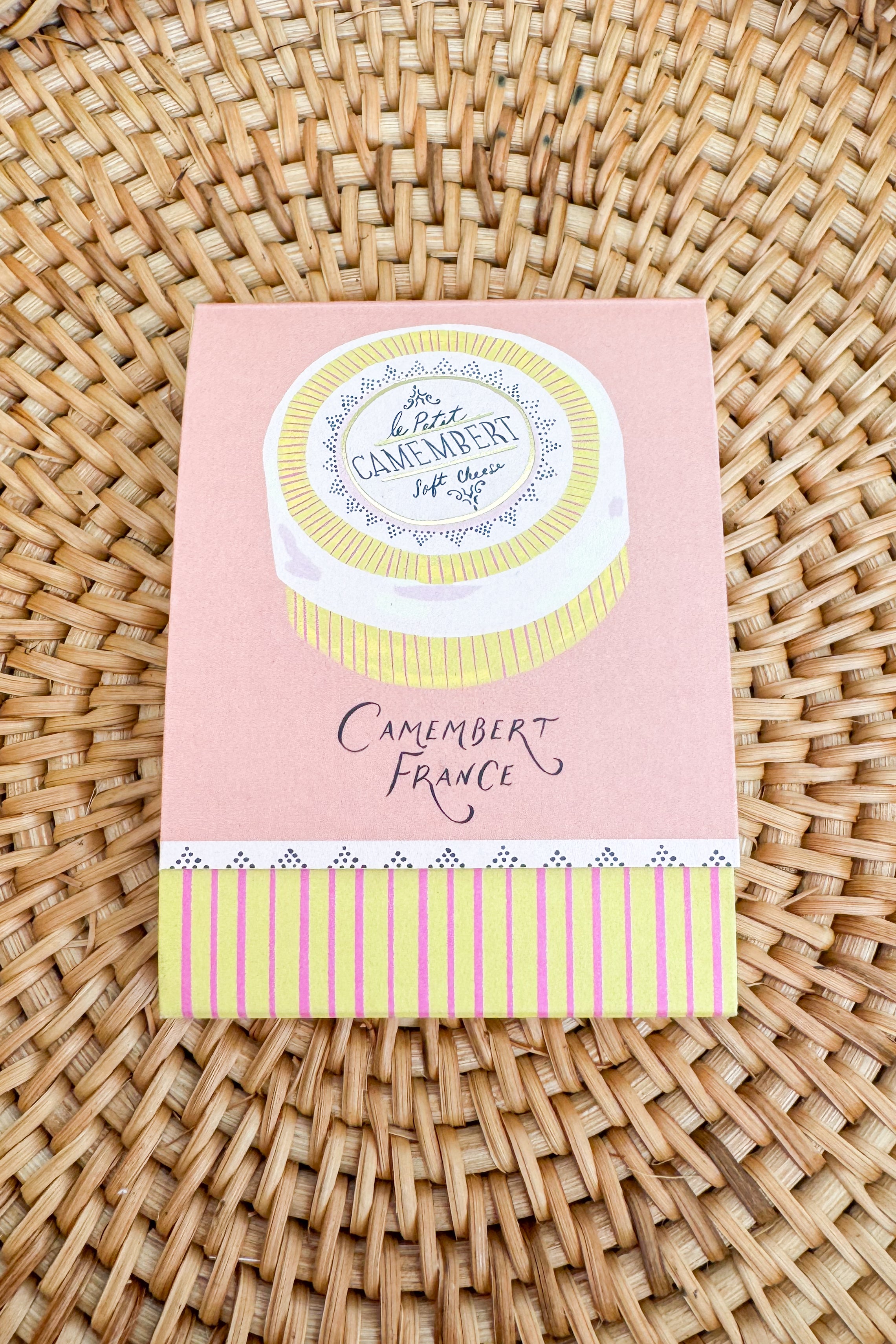 Pink packaging with a white label featuring text and graphics on a woven surface