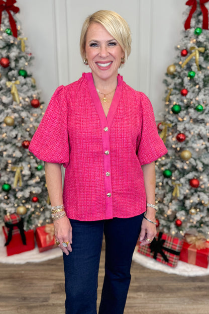 Woman wearing a pink blouse with Christmas trees and decorations in the background