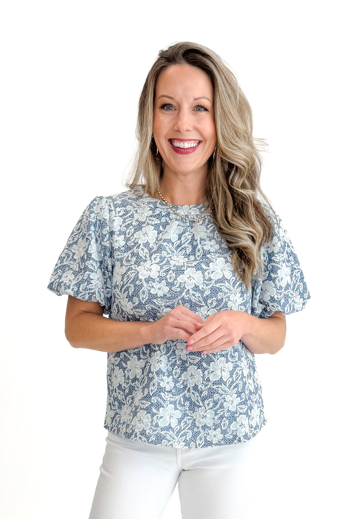 Front view of woman wearing Light Blue Floral Textured Top with jeans against white studio background.