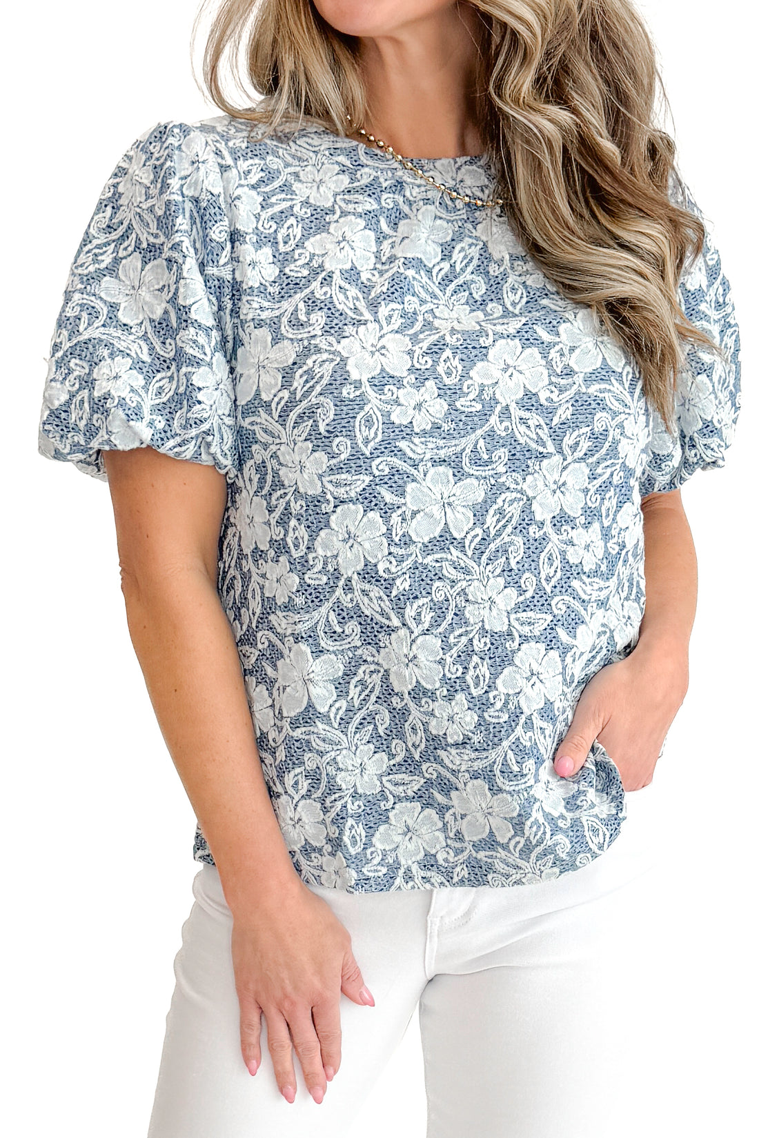 Front detail view of woman wearing Light Blue Floral Textured Top with jeans against white studio background.