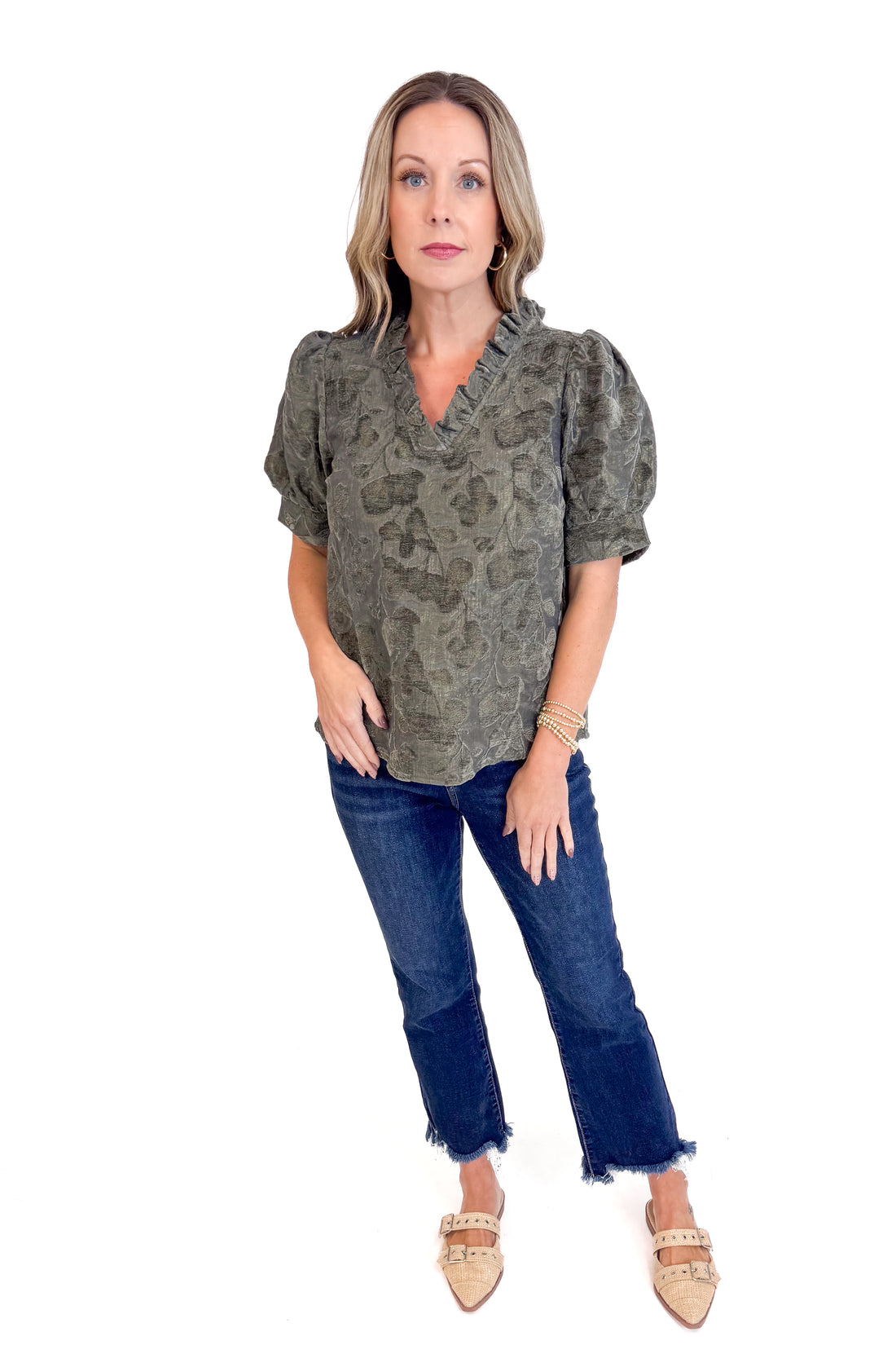 Woman wearing a patterned blouse and blue jeans on a white background