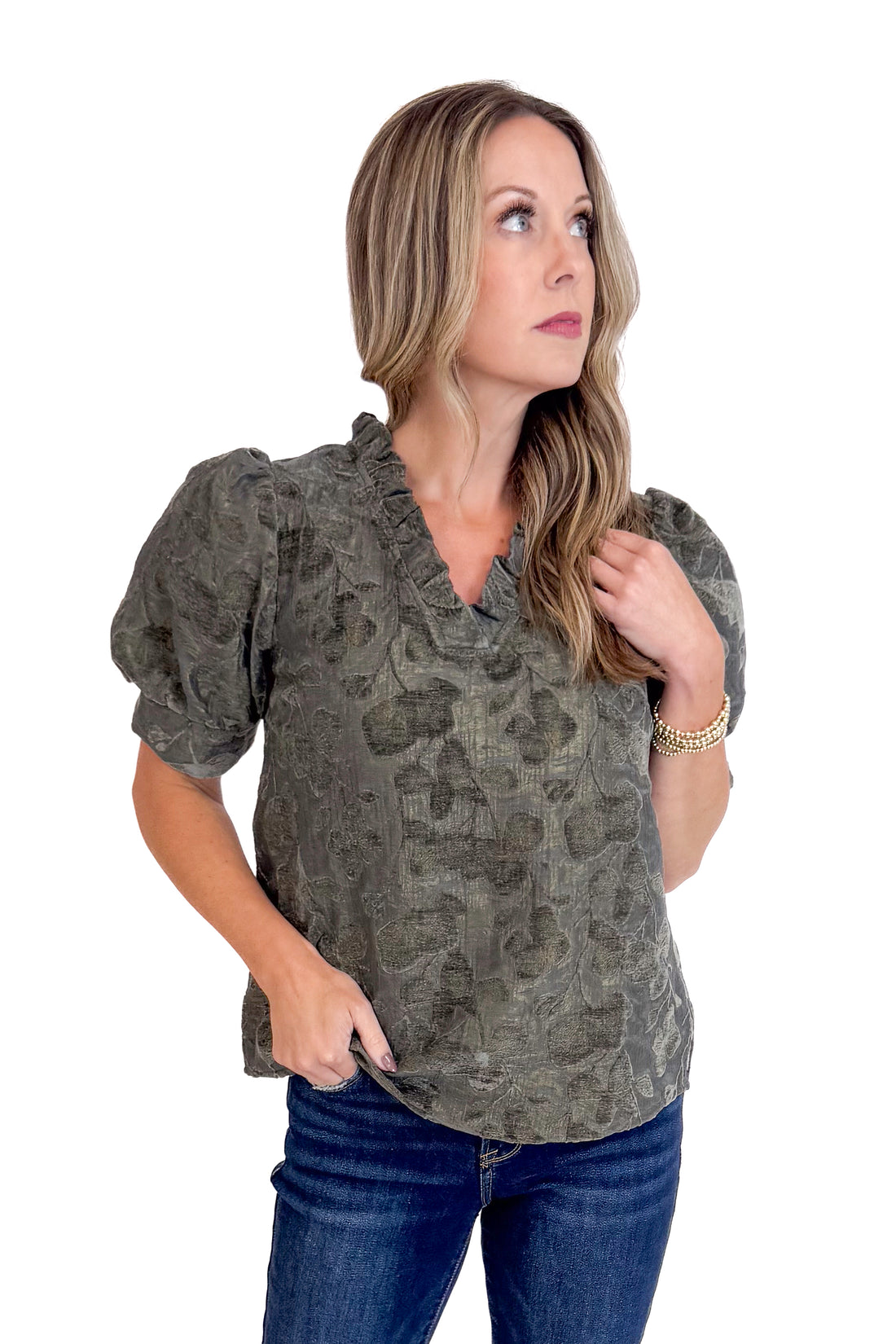 Woman wearing a patterned blouse and jeans on a white background