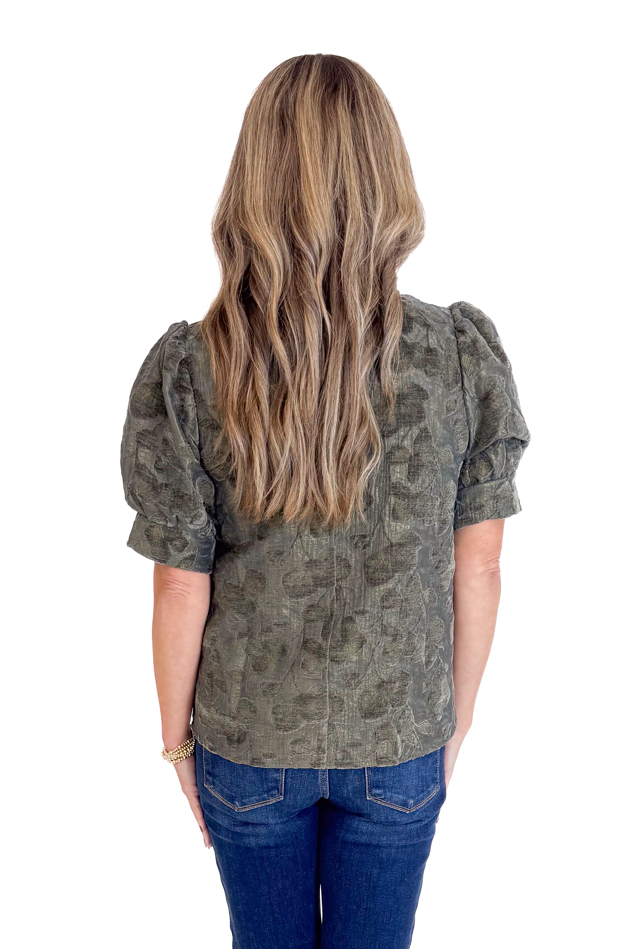 Person wearing a patterned blouse and blue jeans on a white background