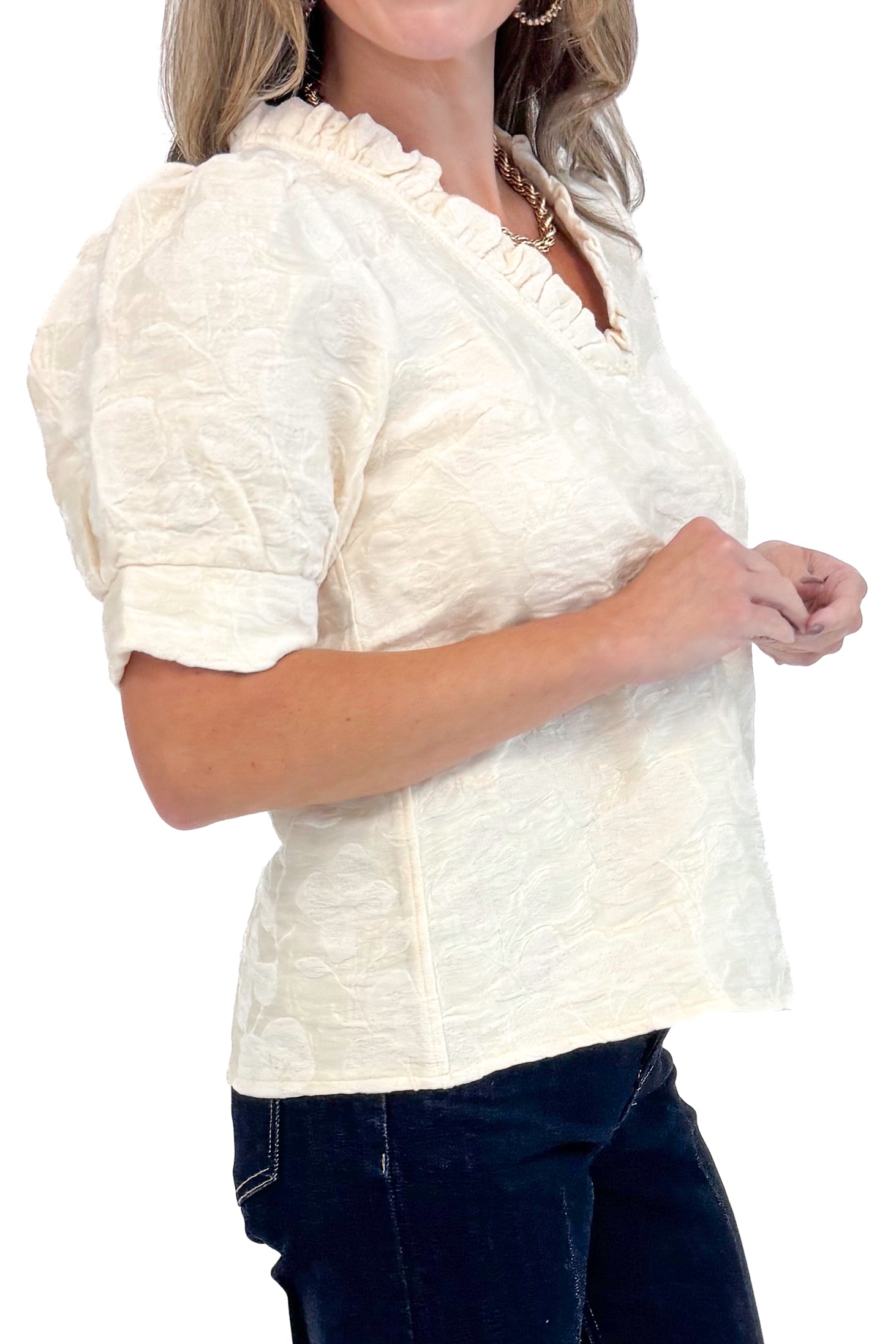 Side detail view of woman wearing Cream Floral Textured V-neck Top and blue jeans. 