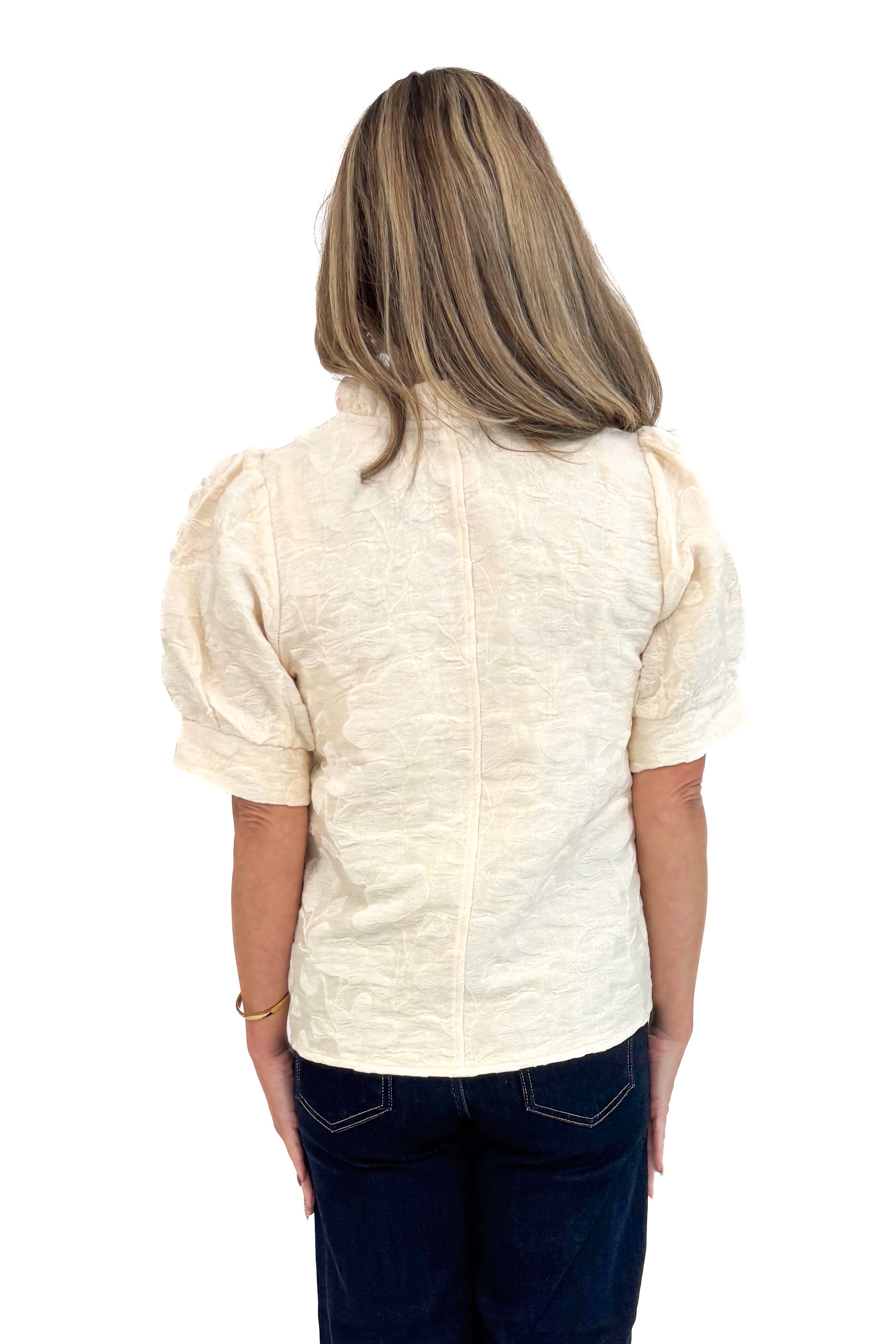 Back view of woman wearing Cream Floral Textured V-neck Top and blue jeans. 