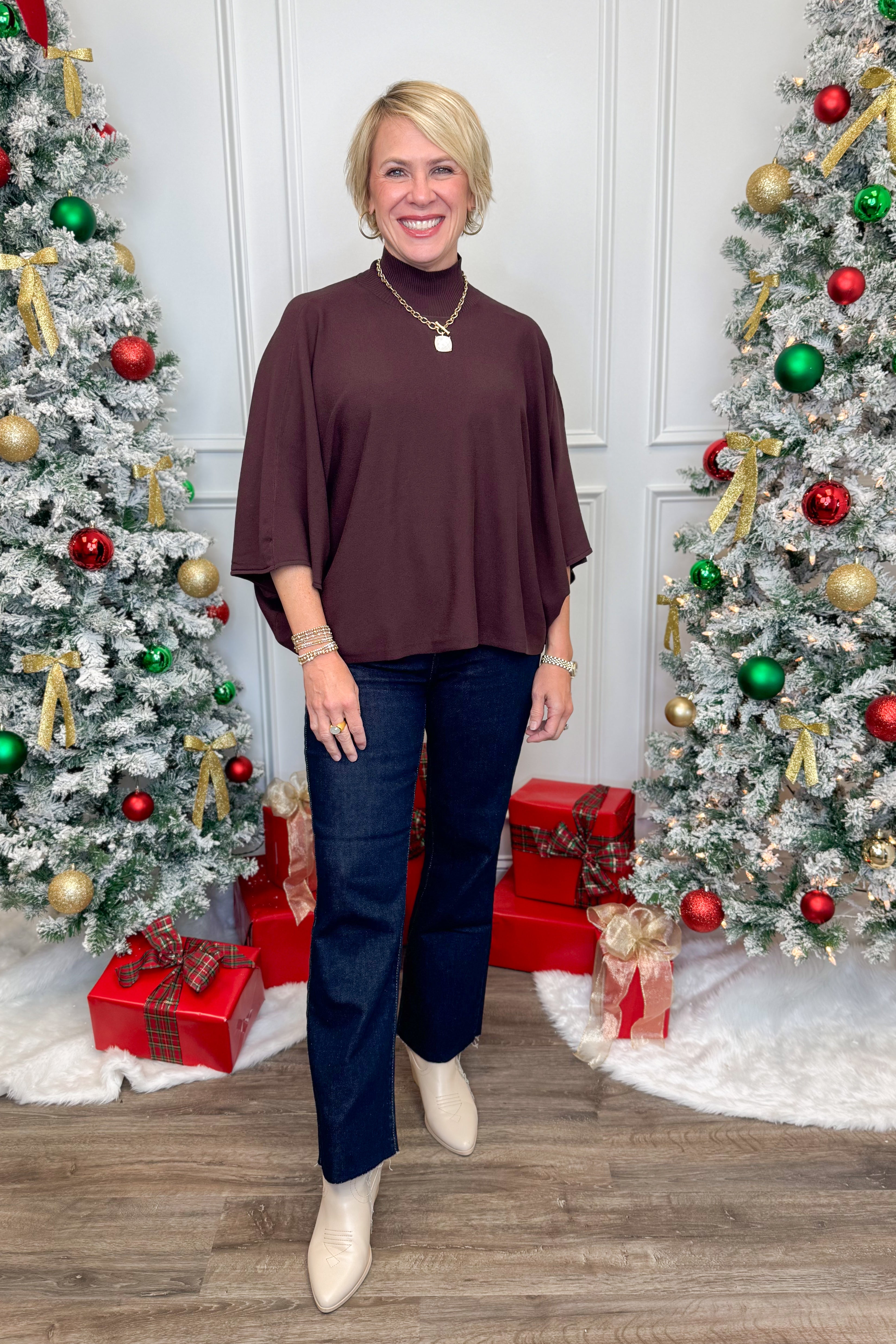 Woman standing in front of Christmas trees with decorated presents.