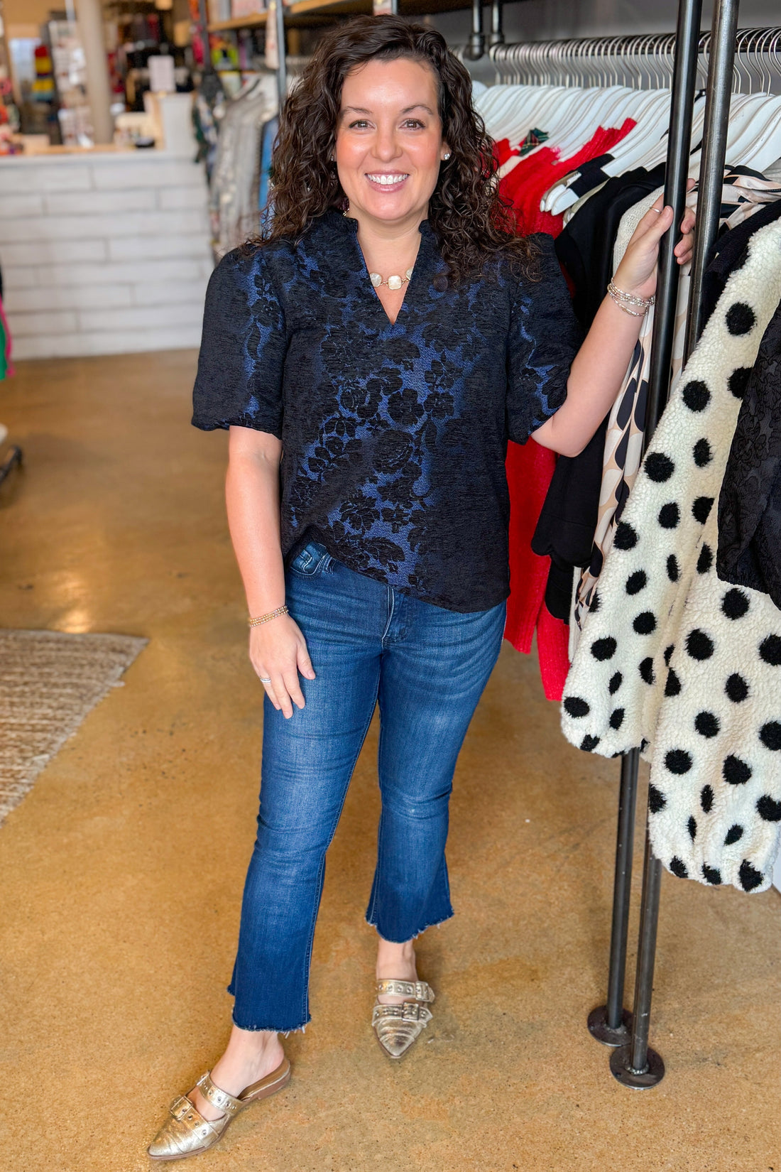 Front view of woman wearing Navy Floral Velvet Jacquard Top with jeans at a boutique.