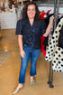 Front view of woman wearing Navy Floral Velvet Jacquard Top with jeans at a boutique.