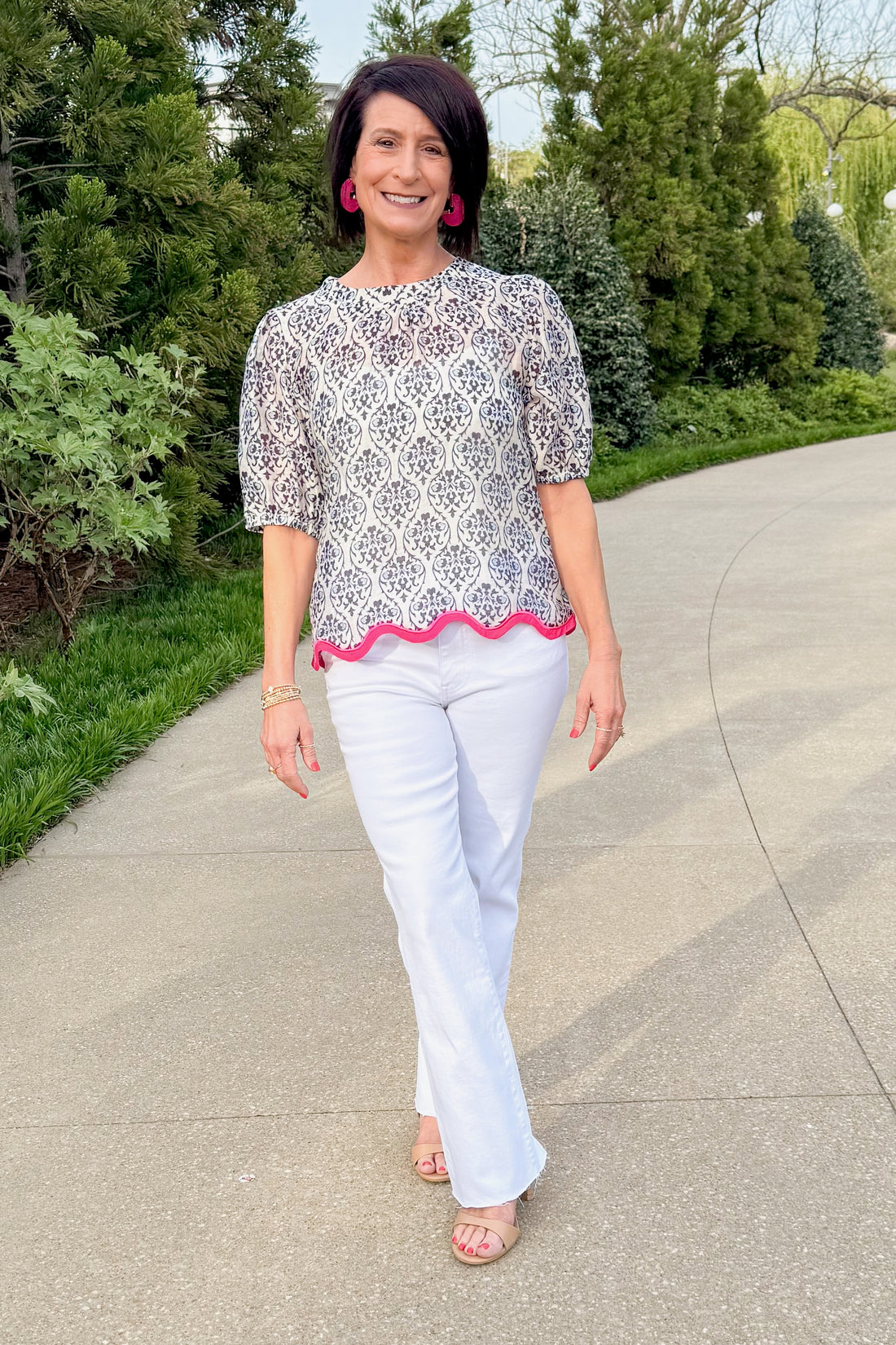 Front view of woman wearing Navy Printed With Hot Pink Hemline Top with jeans outside at a park.
