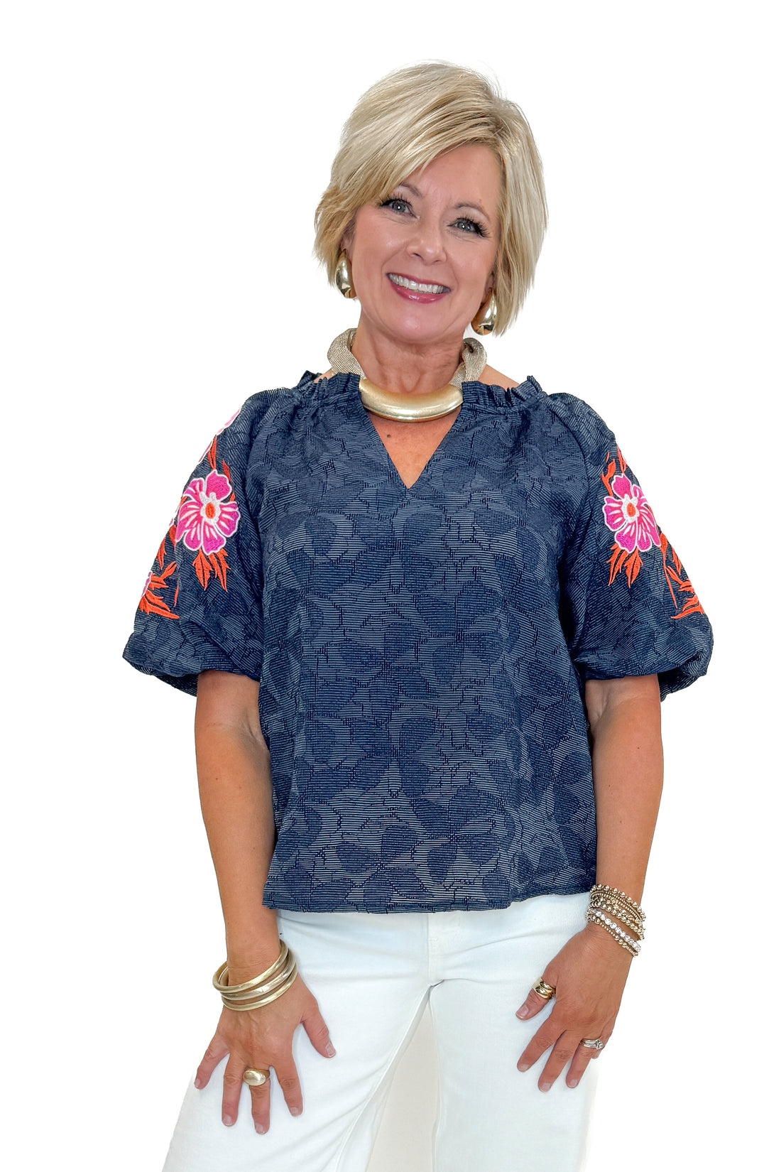 Front view of woman wearing Navy With Floral Embroidered Sleeve Top with jeans against white studio background.