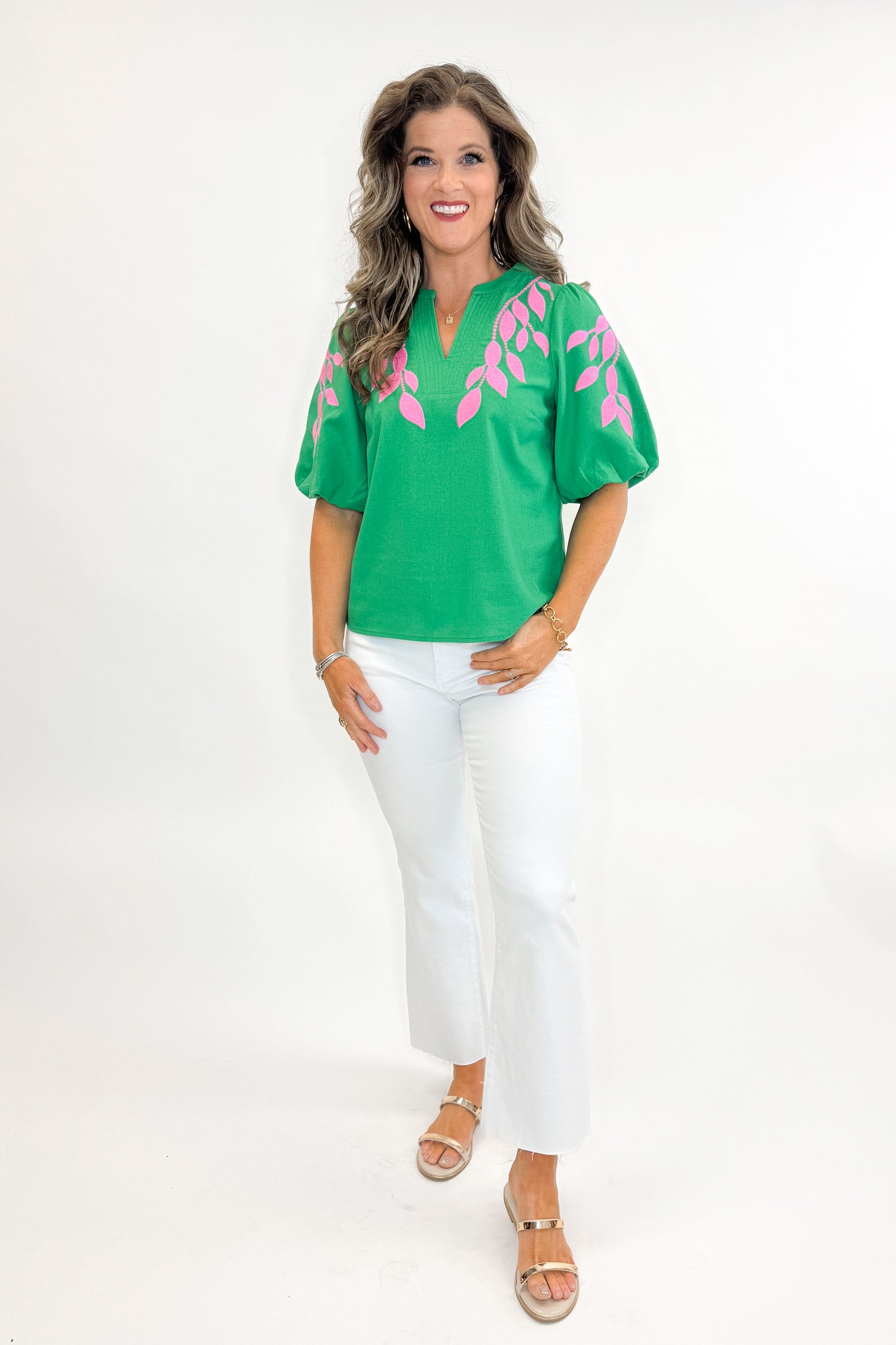 Front view of woman wearing Green &amp; Pink Floral Embroidered V-Neck Top with jeans against white studio background.