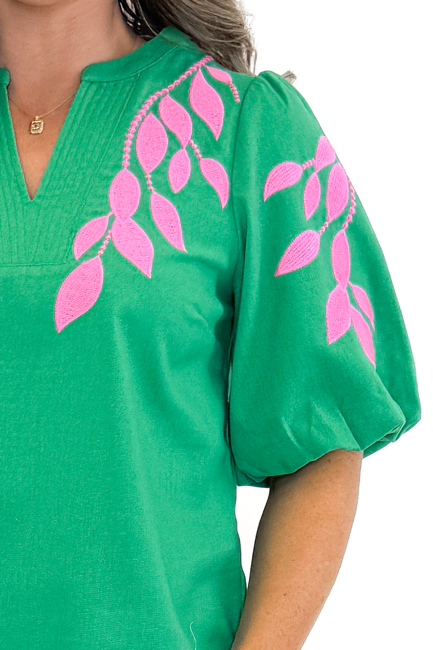Front detail view of woman wearing Green &amp; Pink Floral Embroidered V-Neck Top with jeans against white studio background.