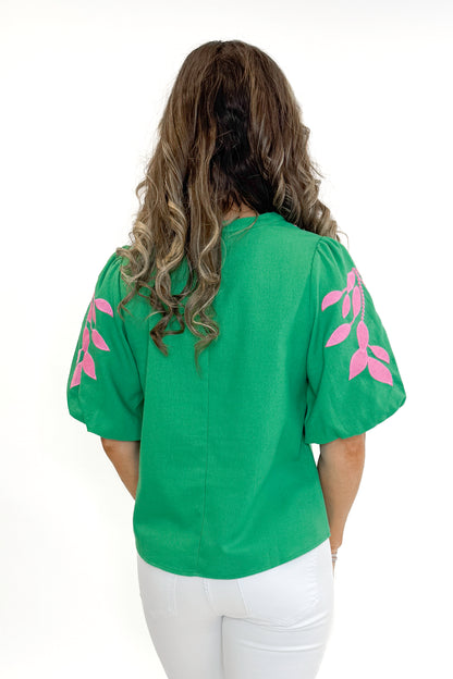 Back view of woman wearing Green &amp; Pink Floral Embroidered V-Neck Top with jeans against white studio background.