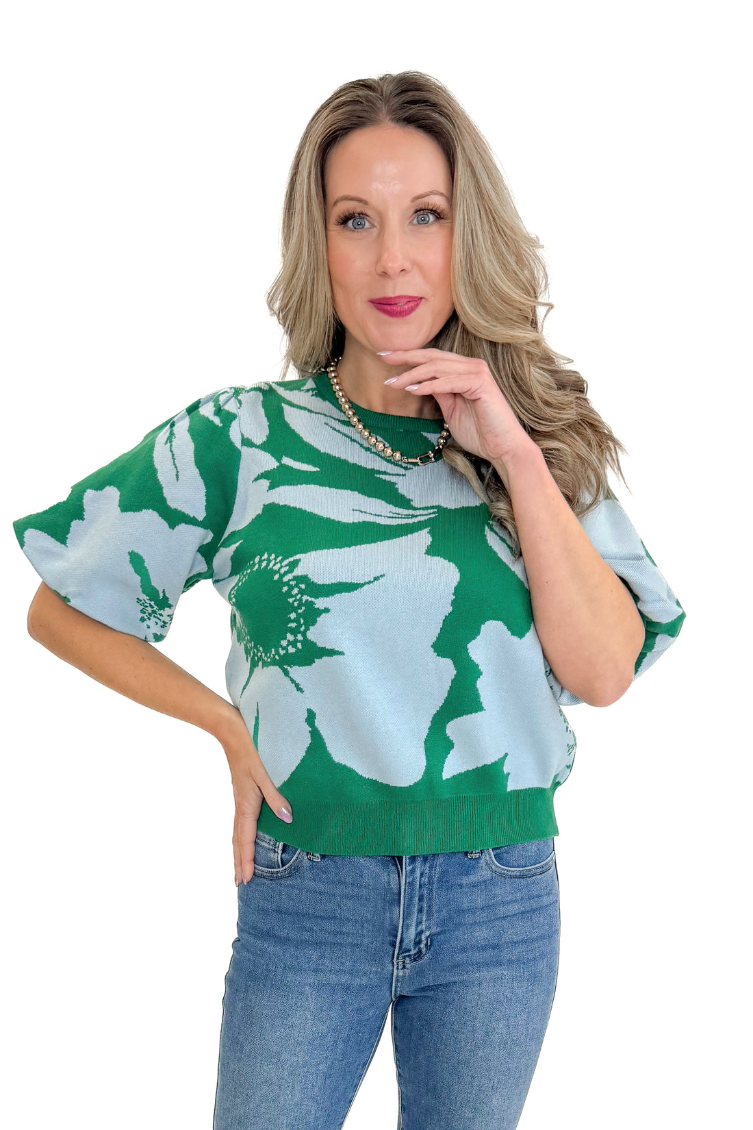 Front view of woman wearing Green &amp; Blue Floral Printed Short Sleeve Sweater with jeans against white studio background.