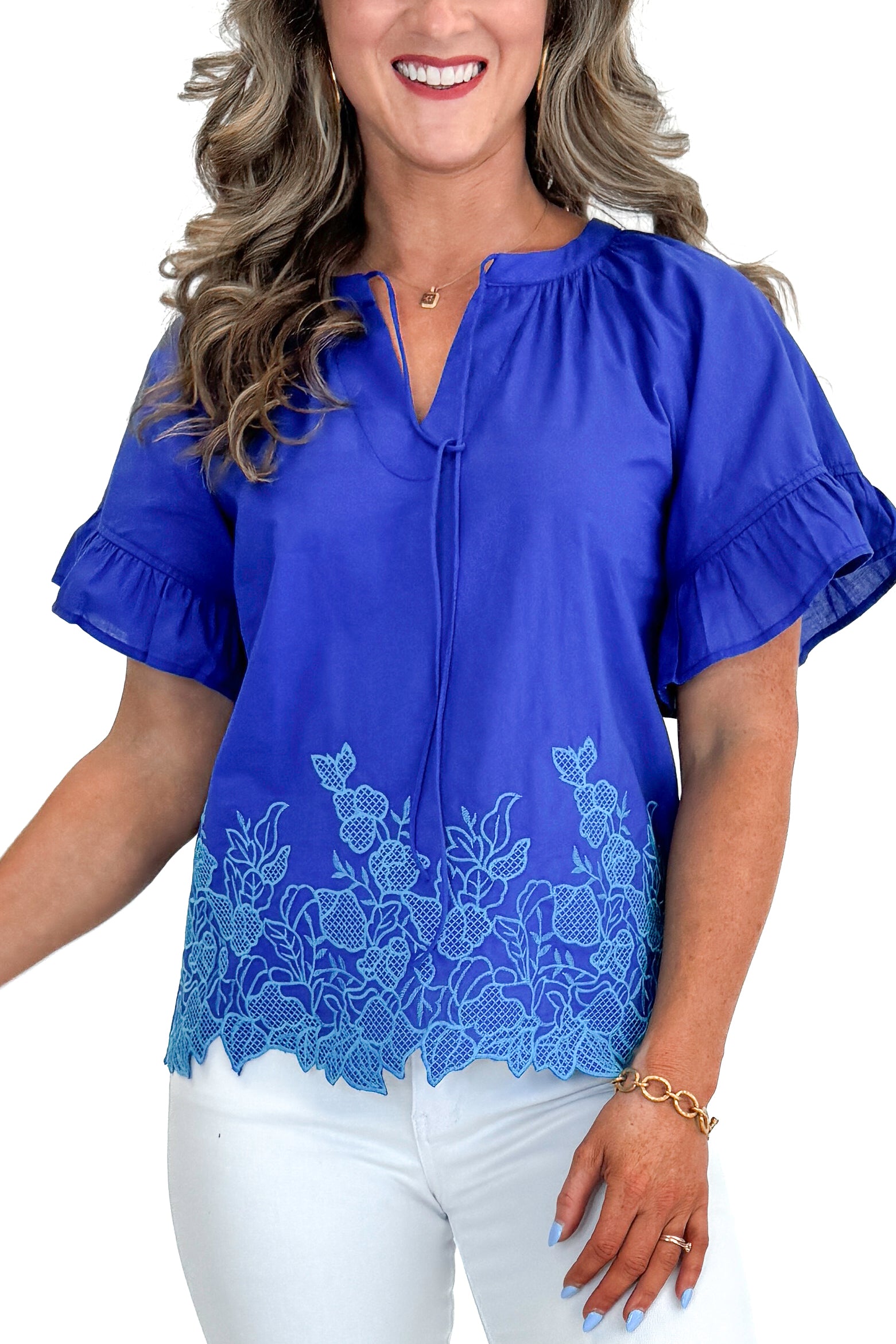 Front detail view of woman wearing Blue Embroidered Hem Top with jeans against white studio background.