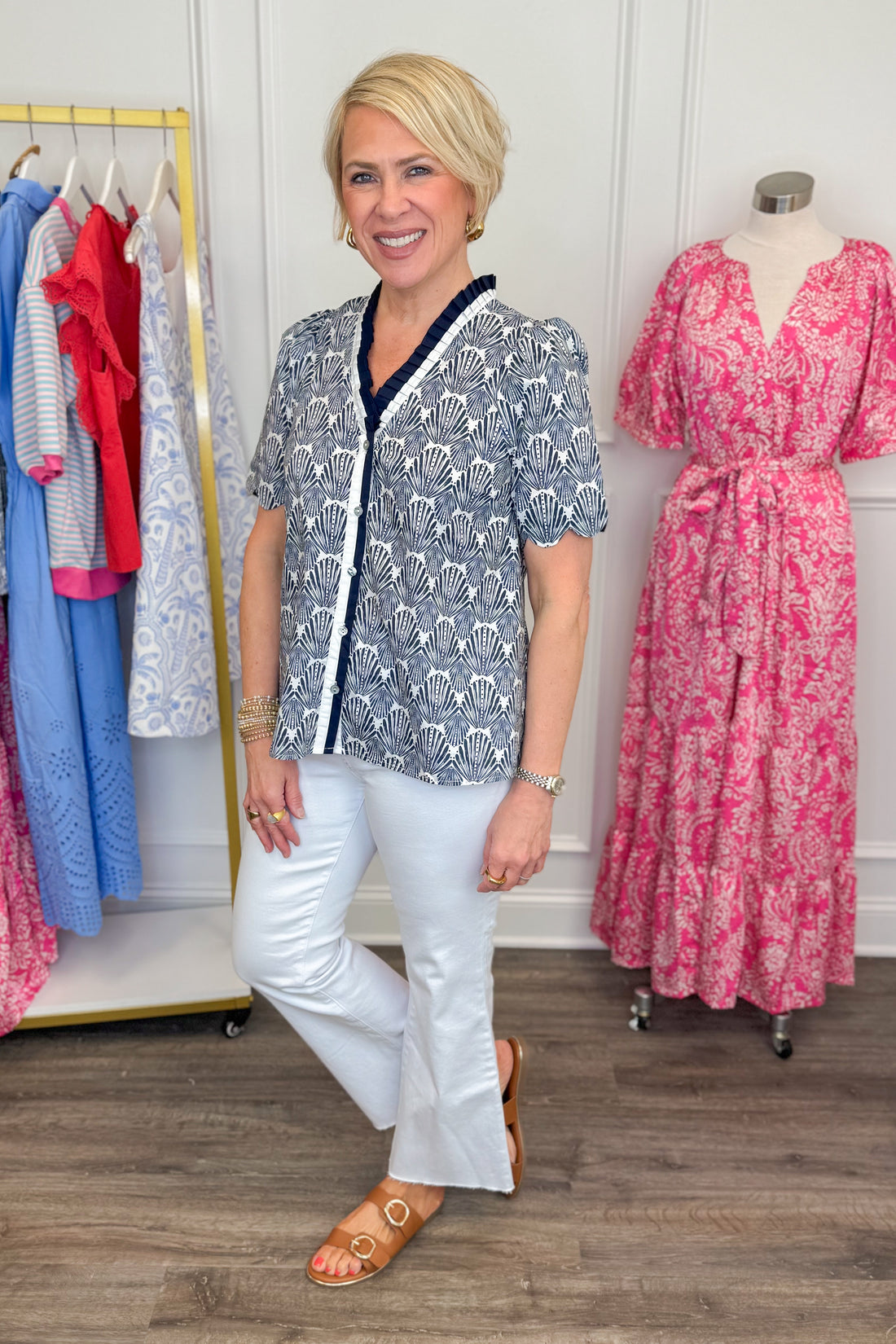 Side view of woman wearing Entro Navy Shell Top with white jeans and sandals.