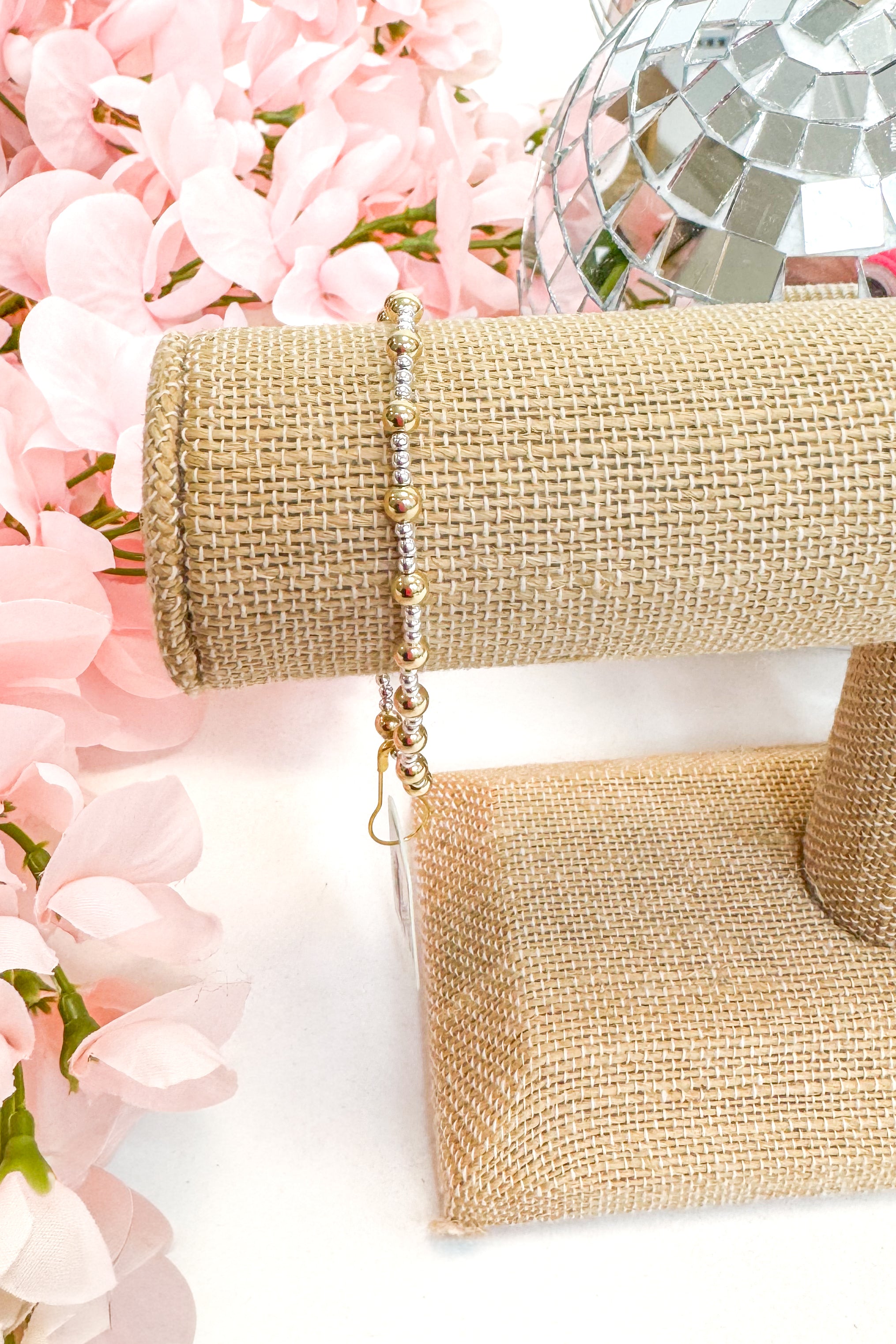 mixed metal enewton bracelet on a white surface with pink flowers and a disco ball in the background