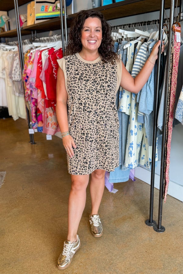 Woman in a leopard print dress standing in a clothing store.