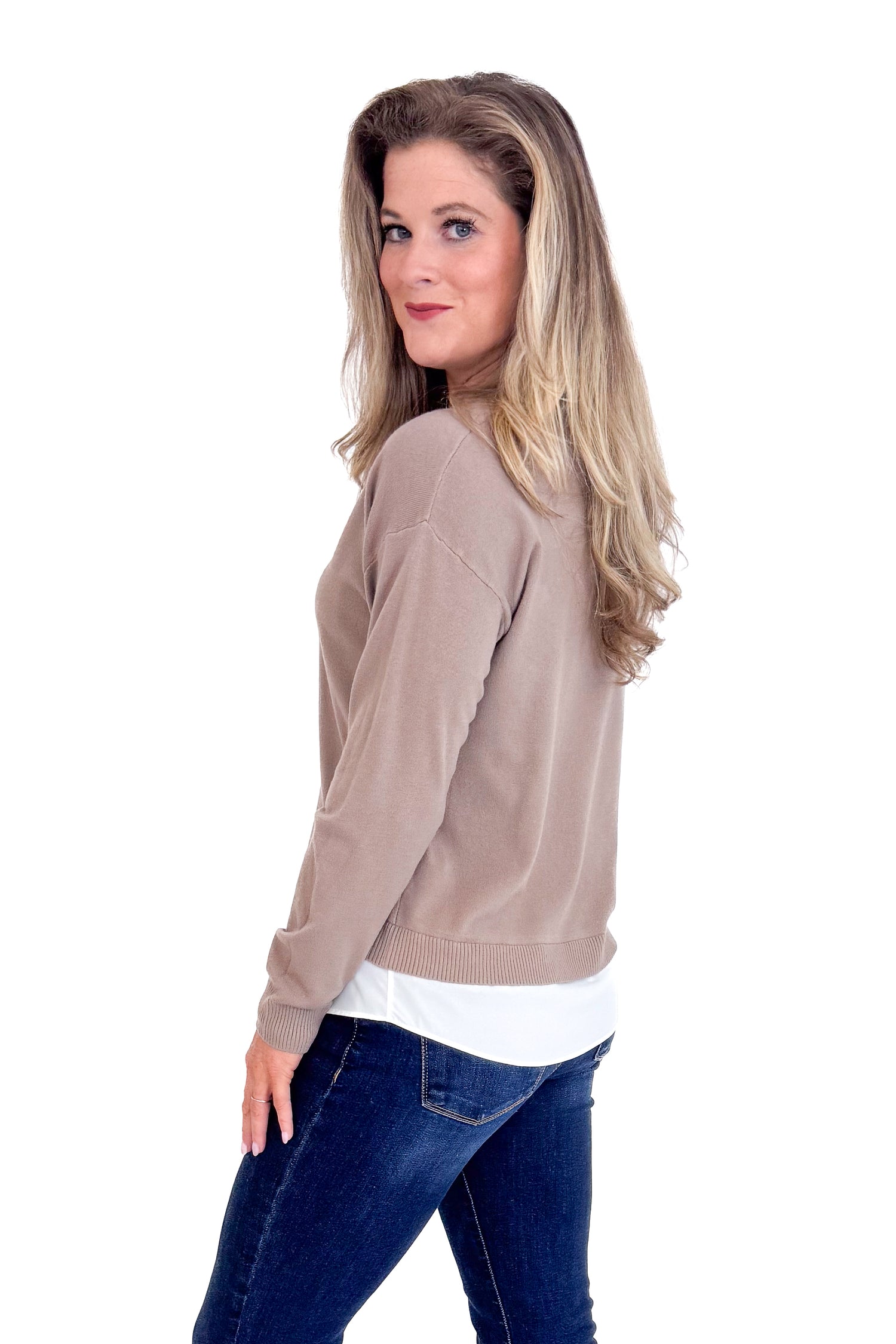 Woman wearing a beige sweater and blue jeans on a white background