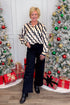 Front view of woman wearing Cream & Black Abstract Print Button Up Top with jeans with holiday decor.