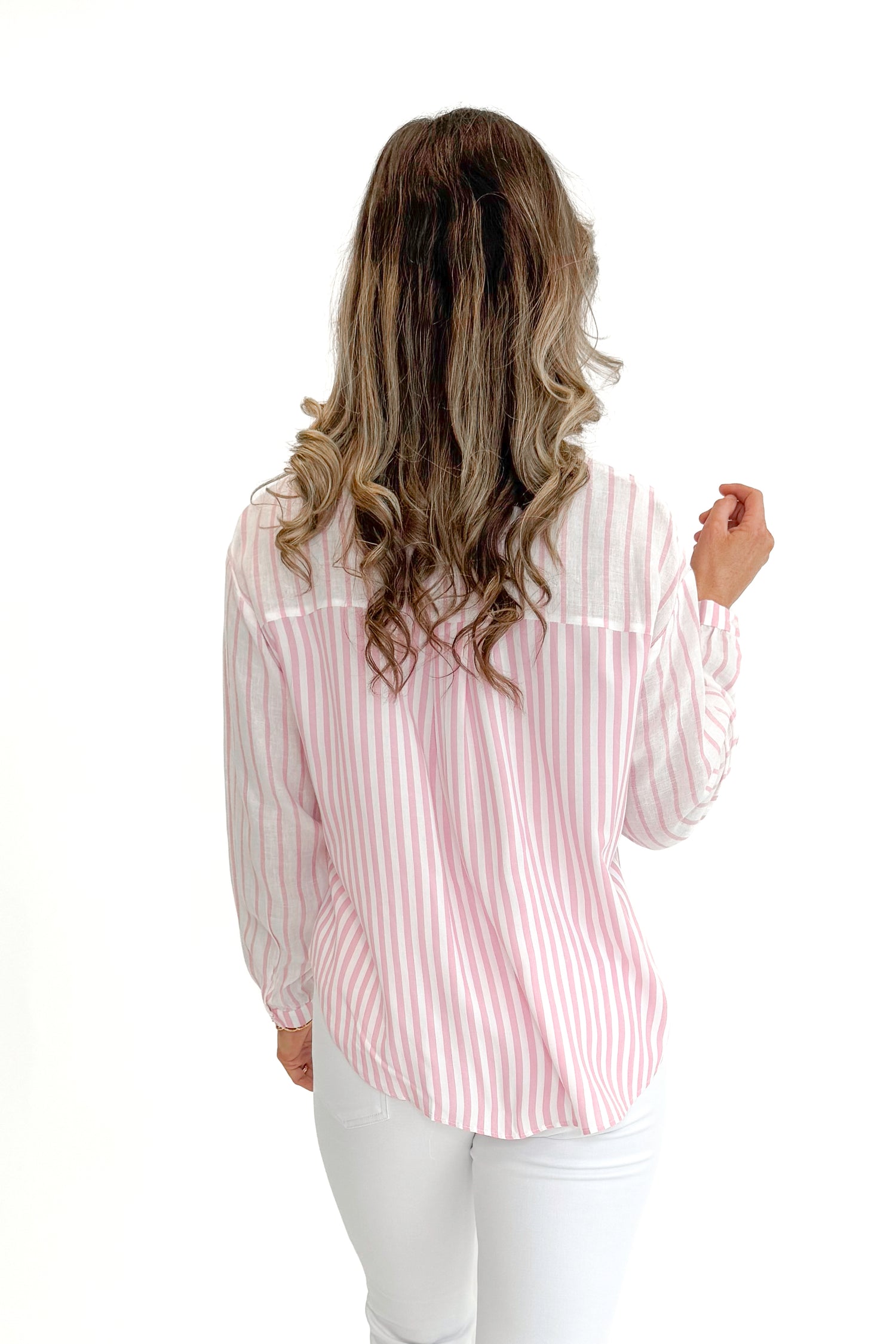 Back view of woman wearing Pink Striped Twist Top by Skies Are Blue with jeans against white studio background.