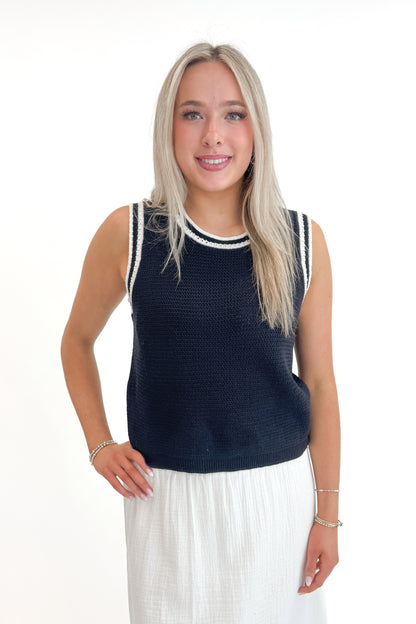 Front view of woman wearing Navy With White Lining Sweater Tank by Skies Are Blue with skirt against white studio background.