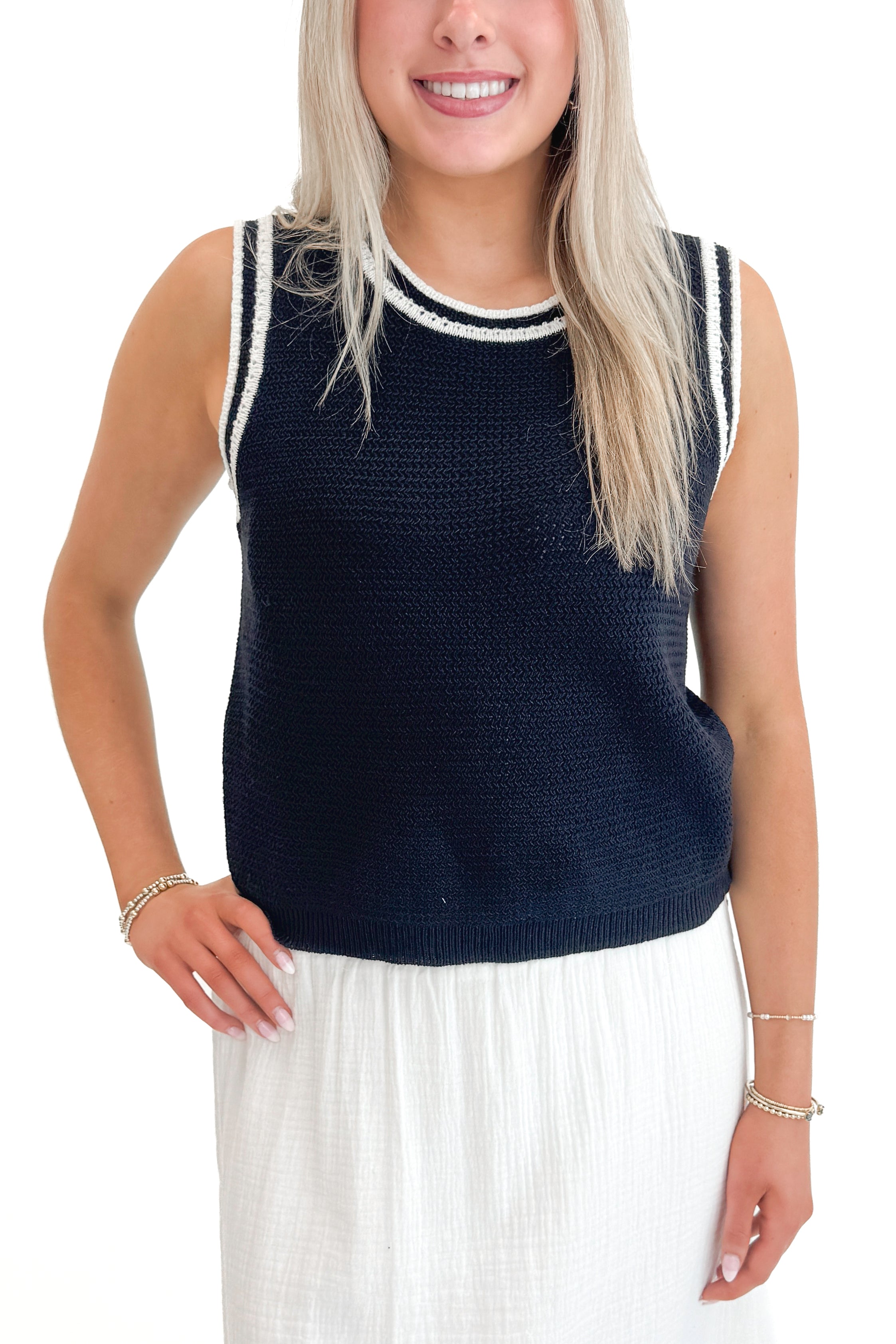 Front detail view of woman wearing Navy With White Lining Sweater Tank by Skies Are Blue with skirt against white studio background.