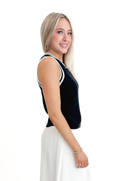 Side view of woman wearing Navy With White Lining Sweater Tank by Skies Are Blue with skirt against white studio background.