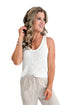 Front view of woman wearing White V-Neck Knitted Tank by Skies Are Blue with pants against white background.