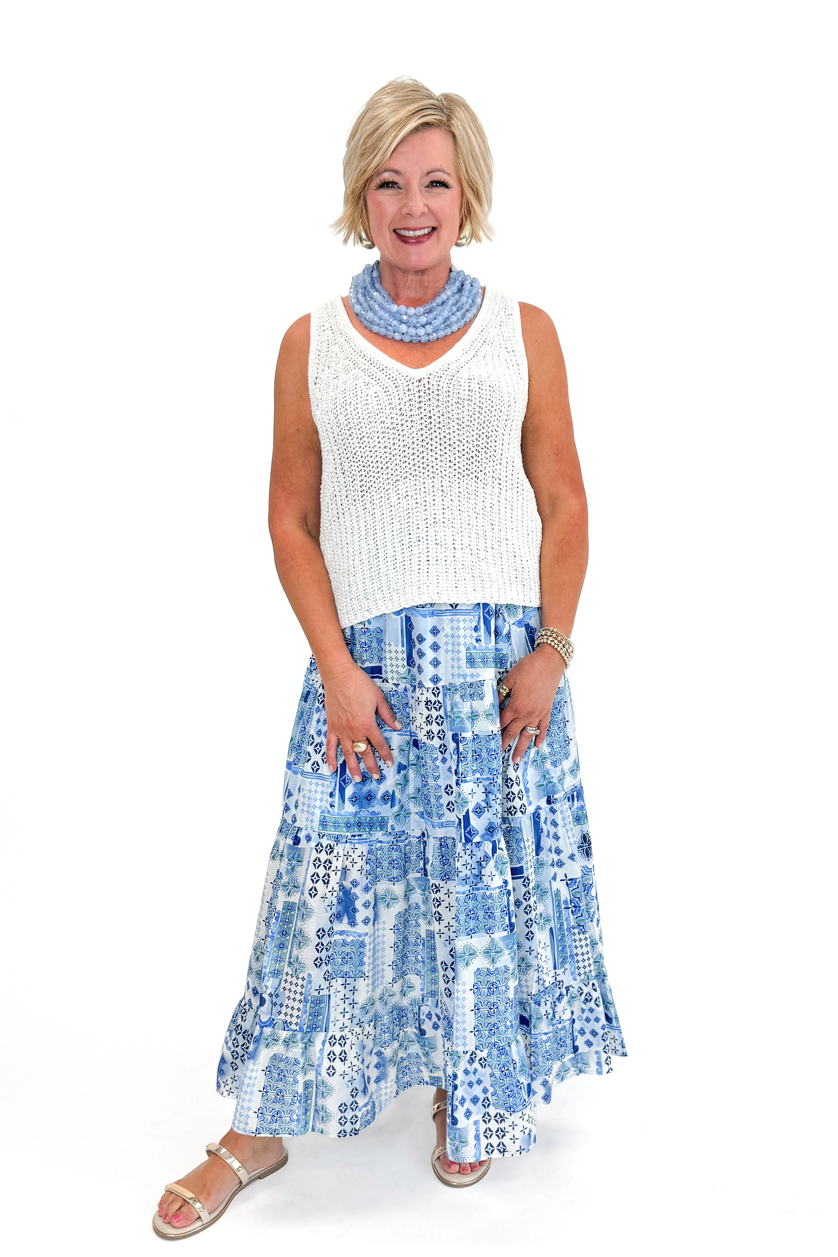 Front view of woman wearing White V-Neck Knitted Tank by Skies Are Blue with skirt against white background.