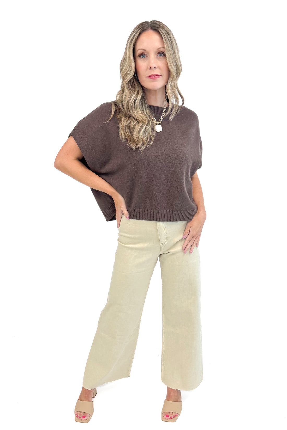 Woman wearing a brown top and beige pants on a white background