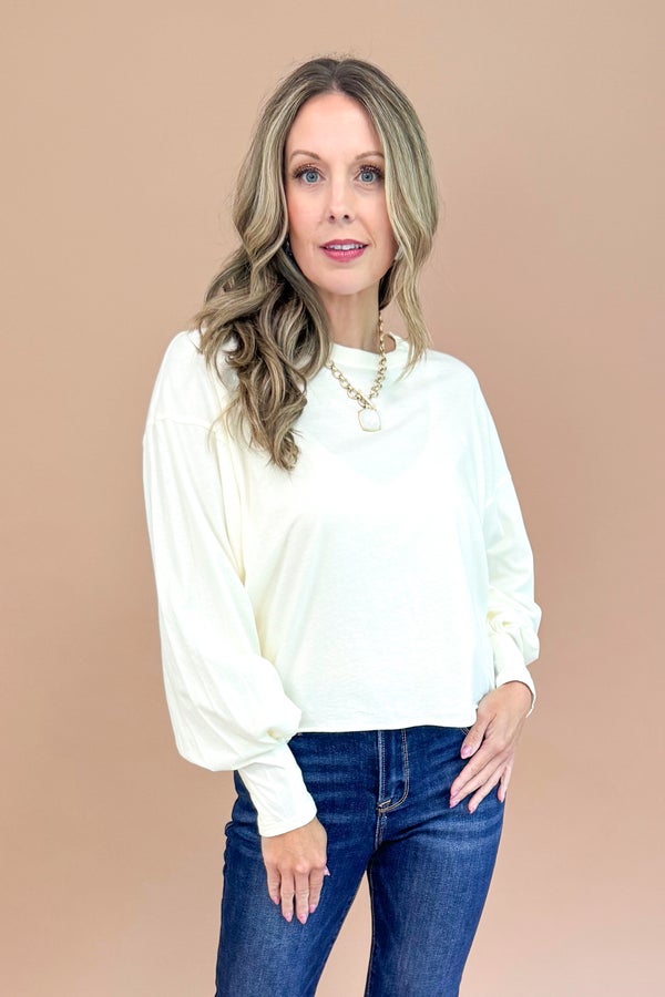 Woman wearing a white blouse and blue jeans against a beige background