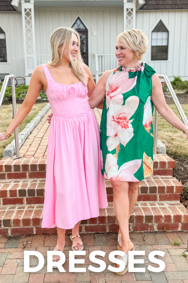 Two women in pink and floral dresses standing on a brick porch with 'DRESSES' text overlay.